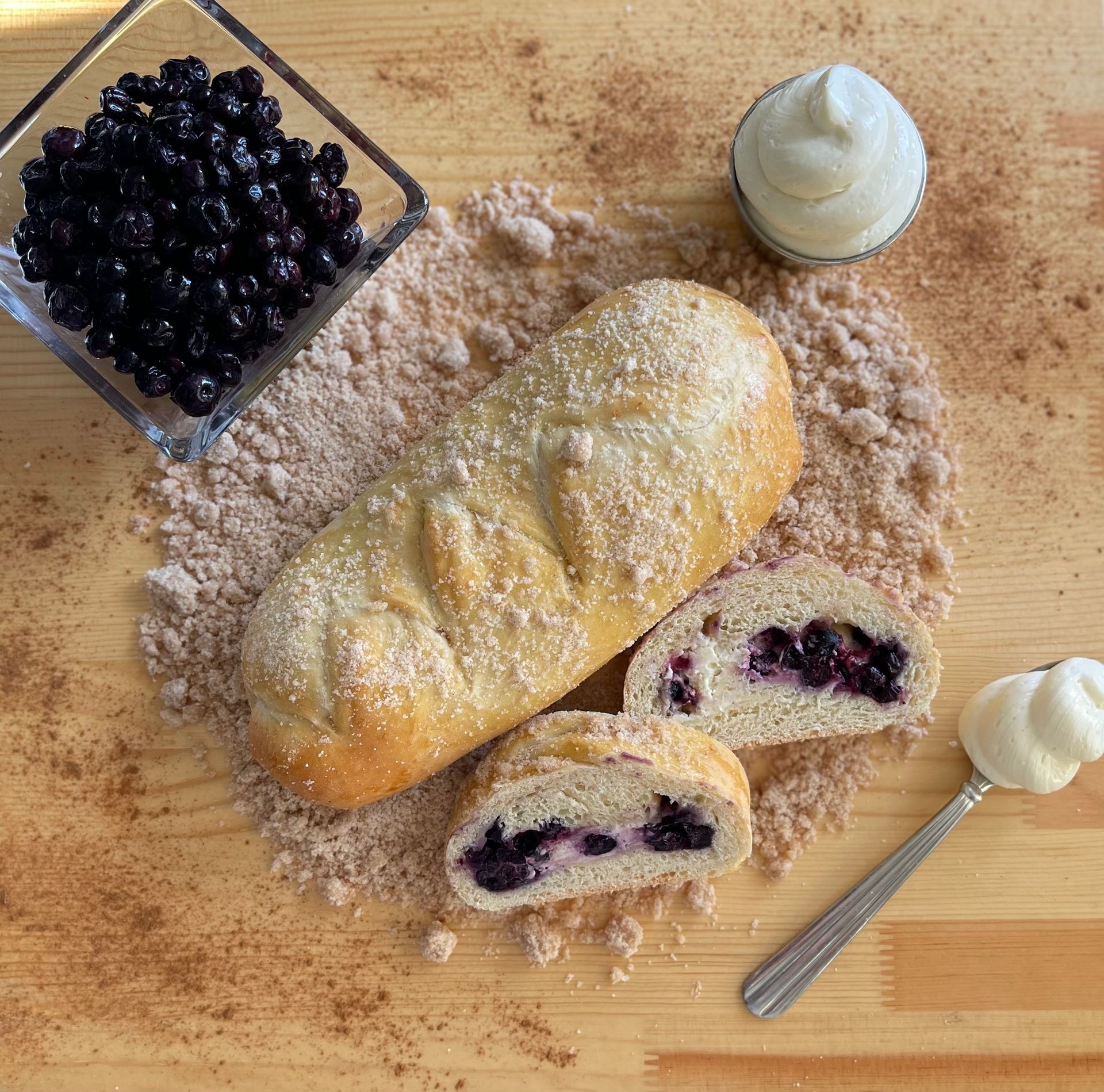 A loaf of bread with blueberries and whipped cream on a wooden table