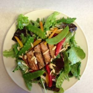 A white plate topped with a salad with meat and vegetables