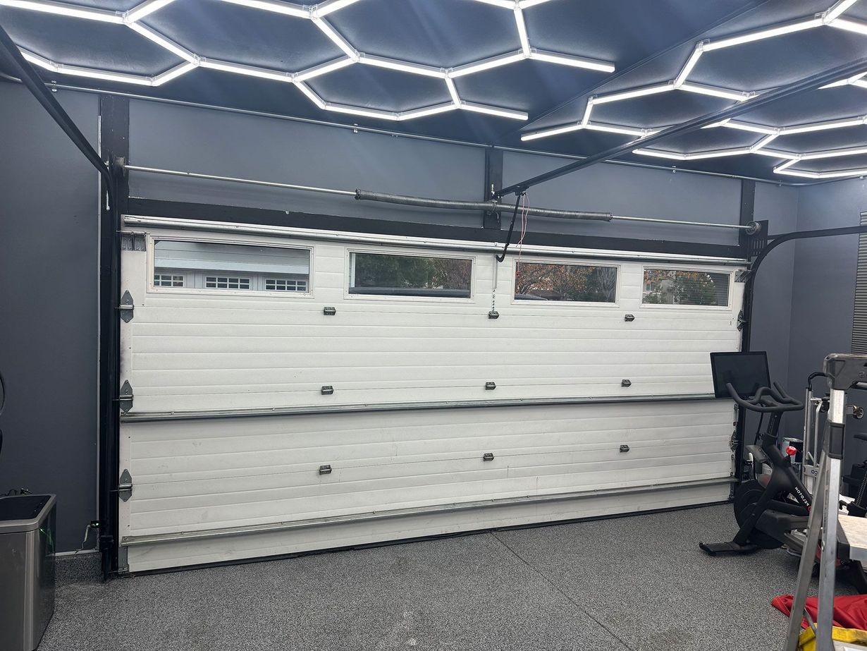 White garage door inside a garage, under honeycomb-shaped LED lights.