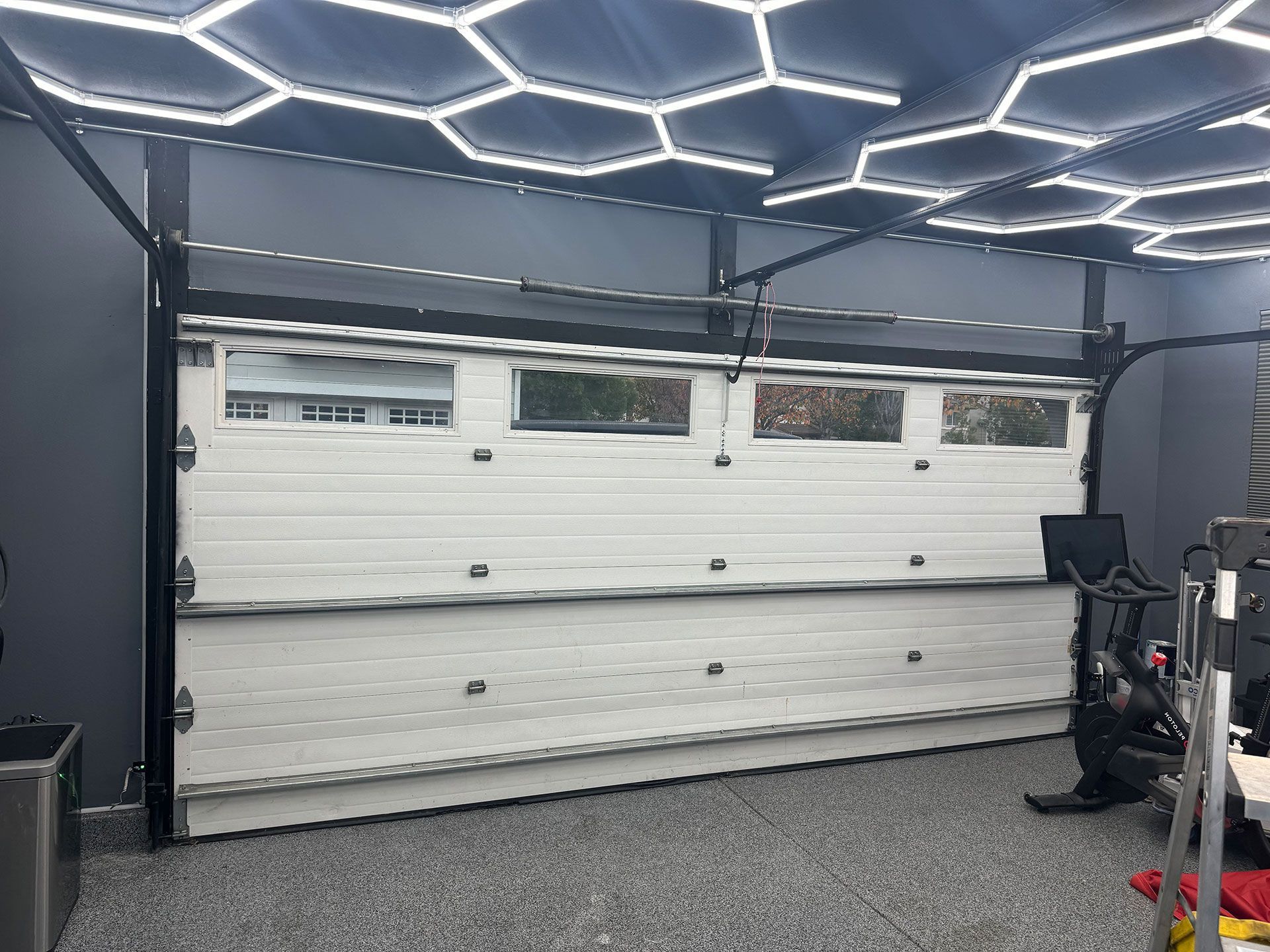 White garage door inside a garage, under honeycomb-shaped LED lights.