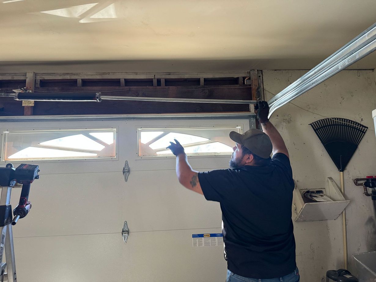 Man in garage, working on the overhead door mechanism.