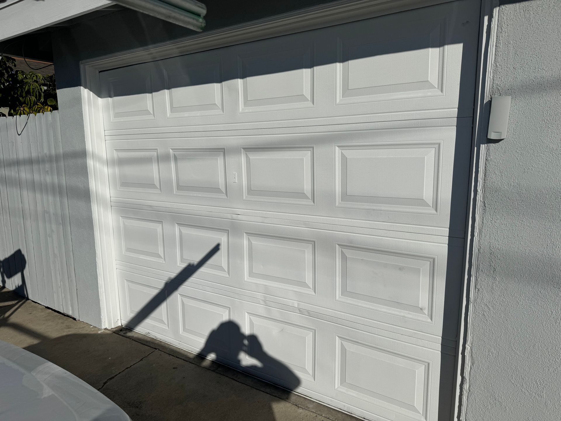 White garage door with rectangular panels on a light-colored building.