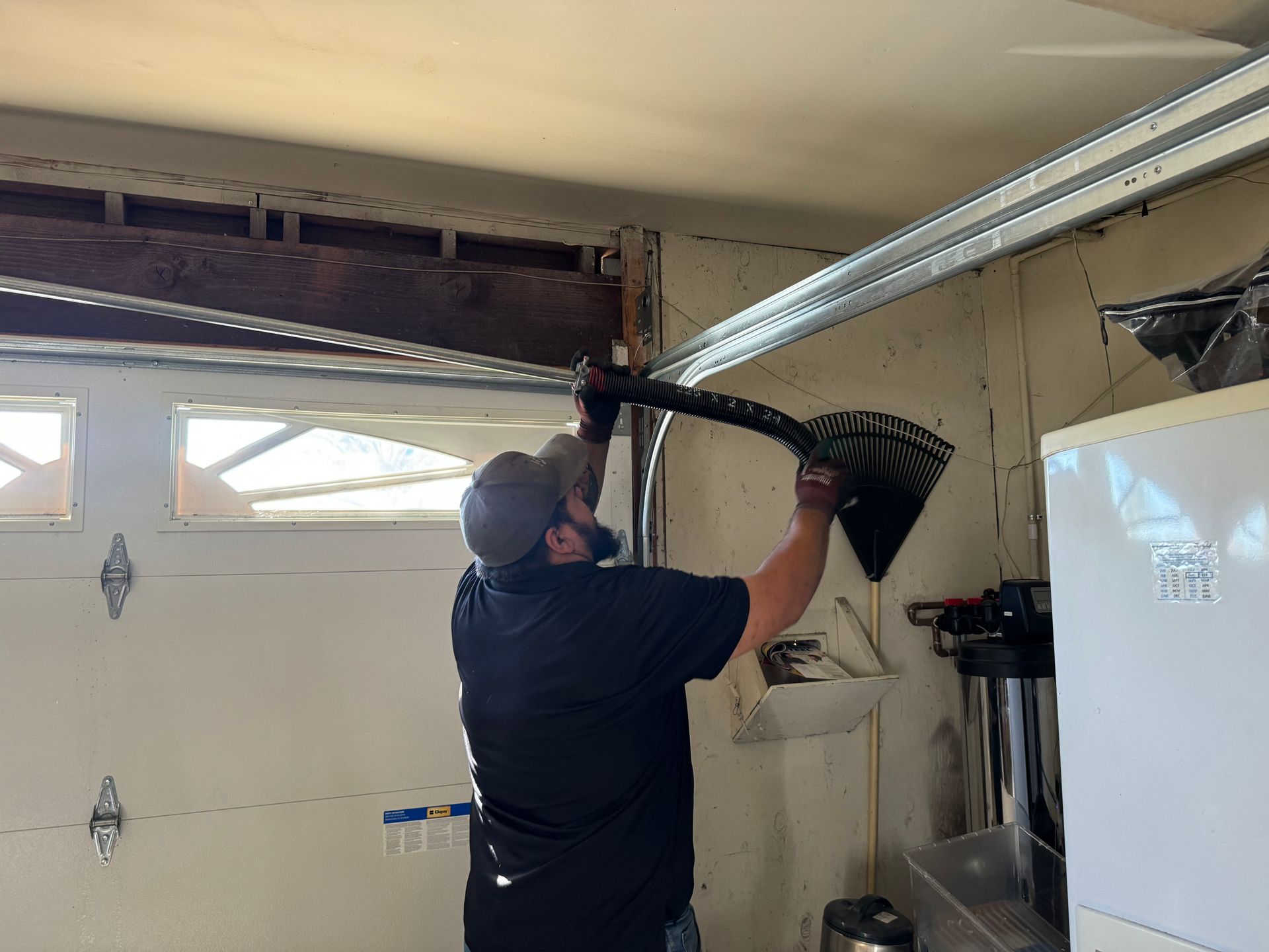 Person installing garage door part, inside a garage.