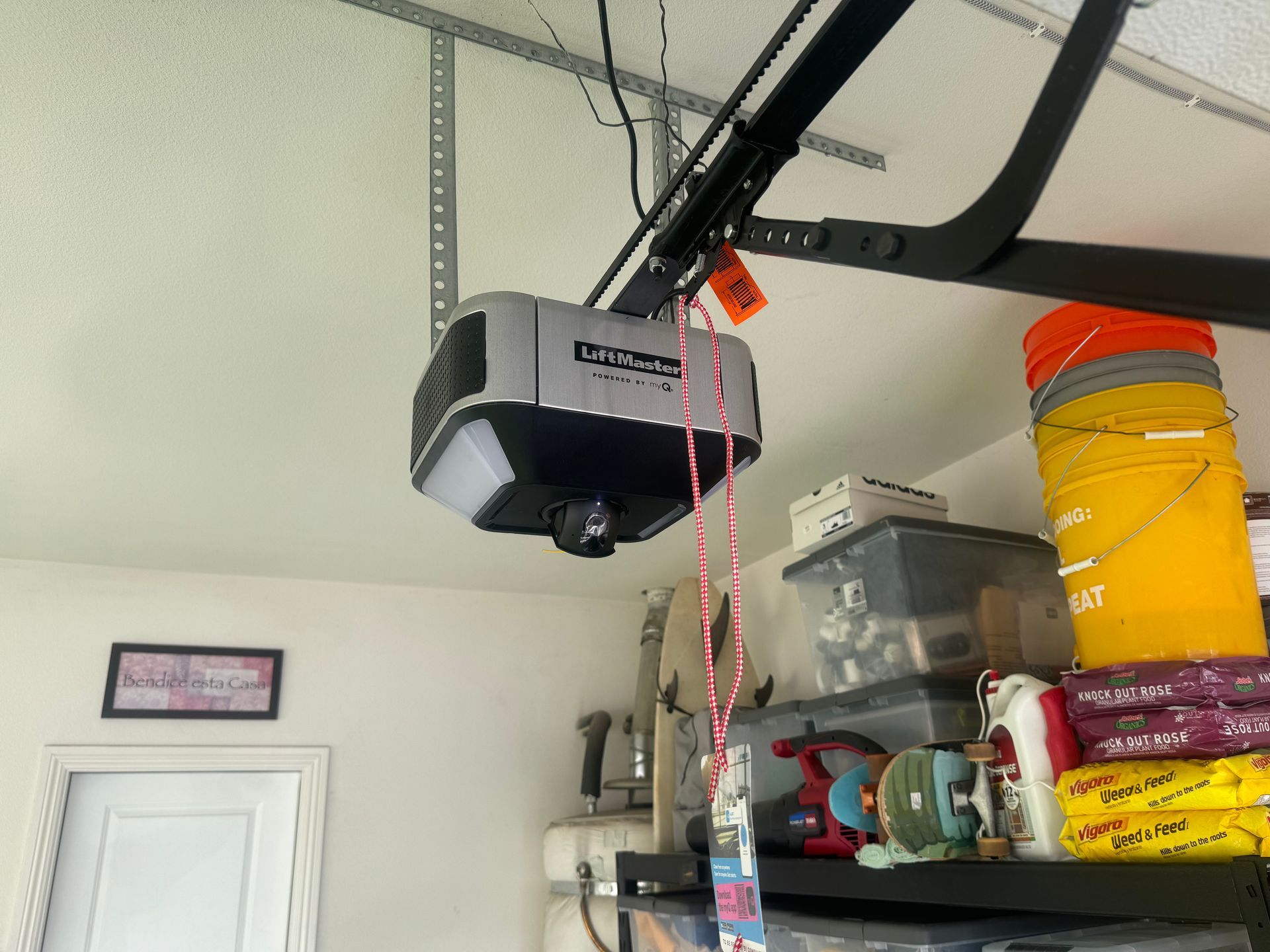 Garage door opener mounted on the ceiling with wires, a door, and storage shelves.