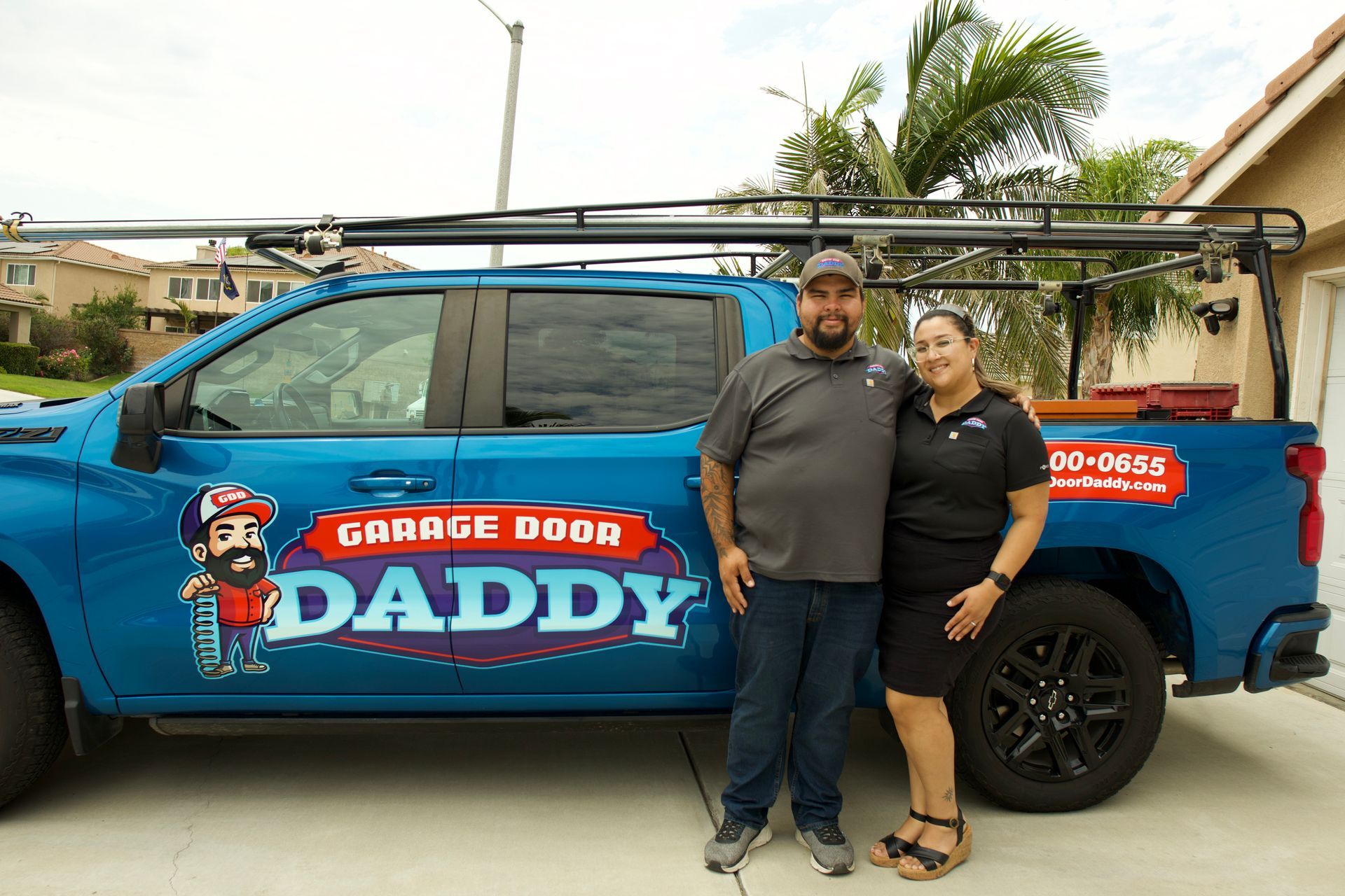 Two people stand next to a blue truck with 