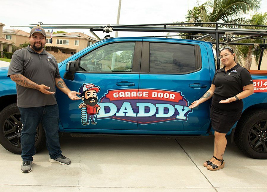 Two people stand next to a teal truck with 