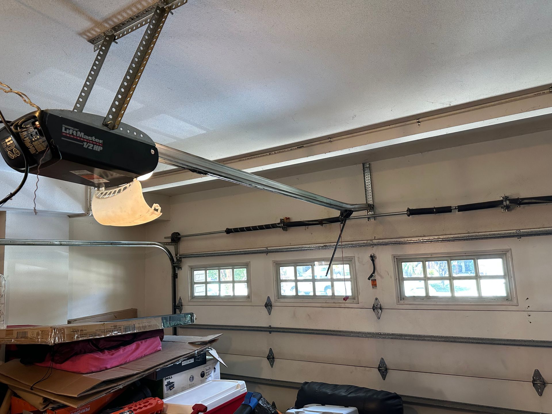 Garage interior with garage door opener on the ceiling and closed garage door with windows.