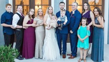 A bride and groom are posing for a picture with their wedding party.