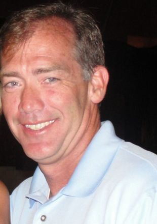 A man in a blue shirt is smiling for the camera