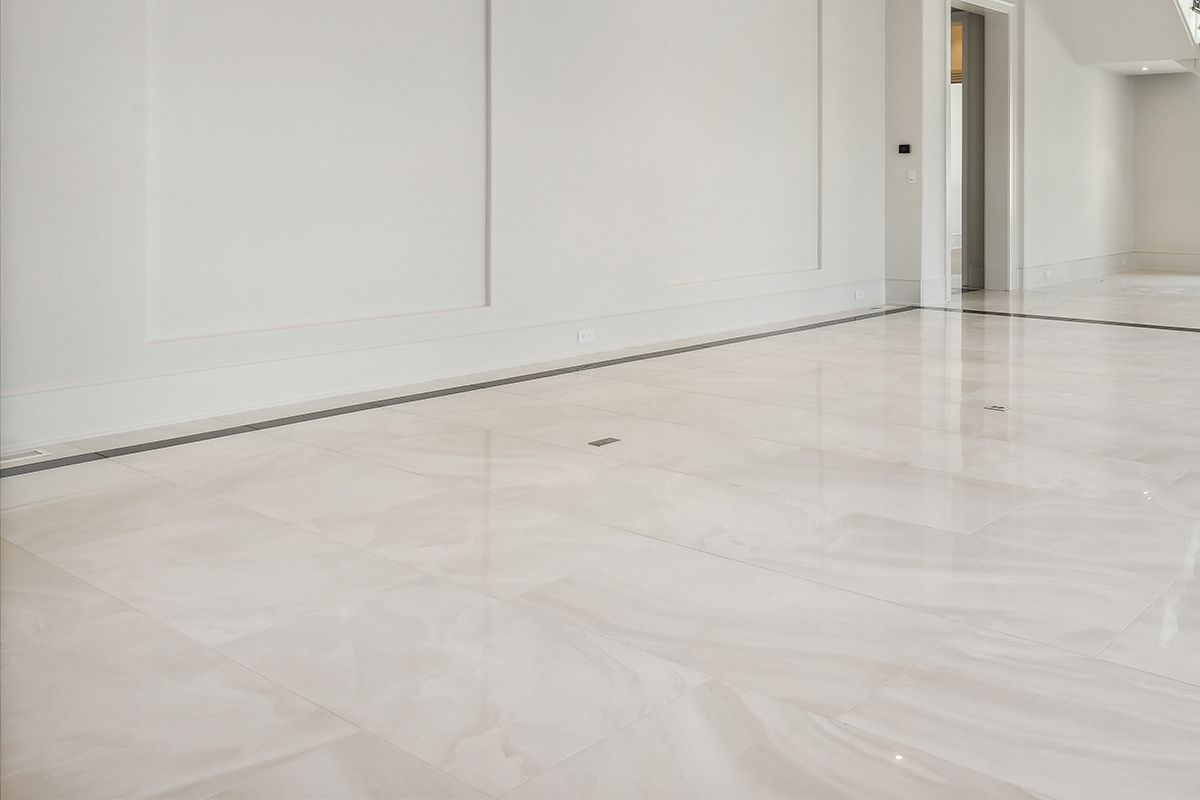 A large empty room with a white marble floor and white walls.
