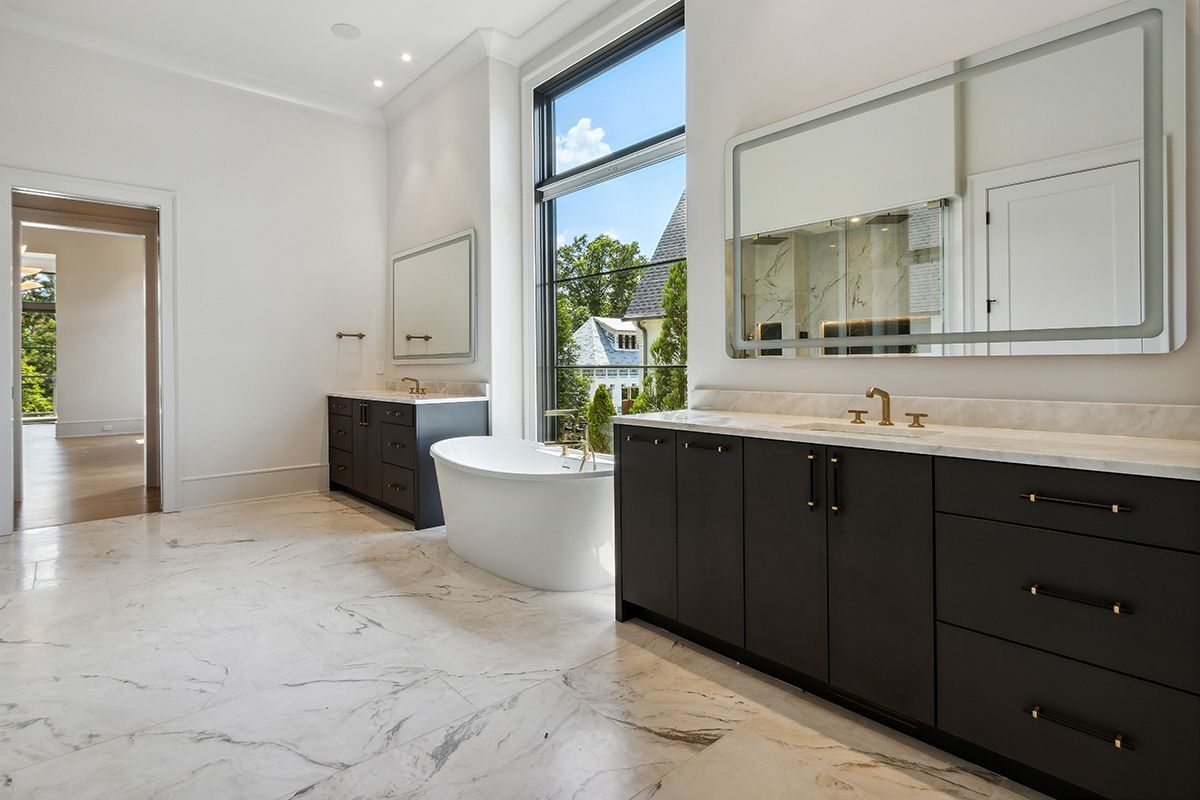 A bathroom with two sinks , a tub and two mirrors.