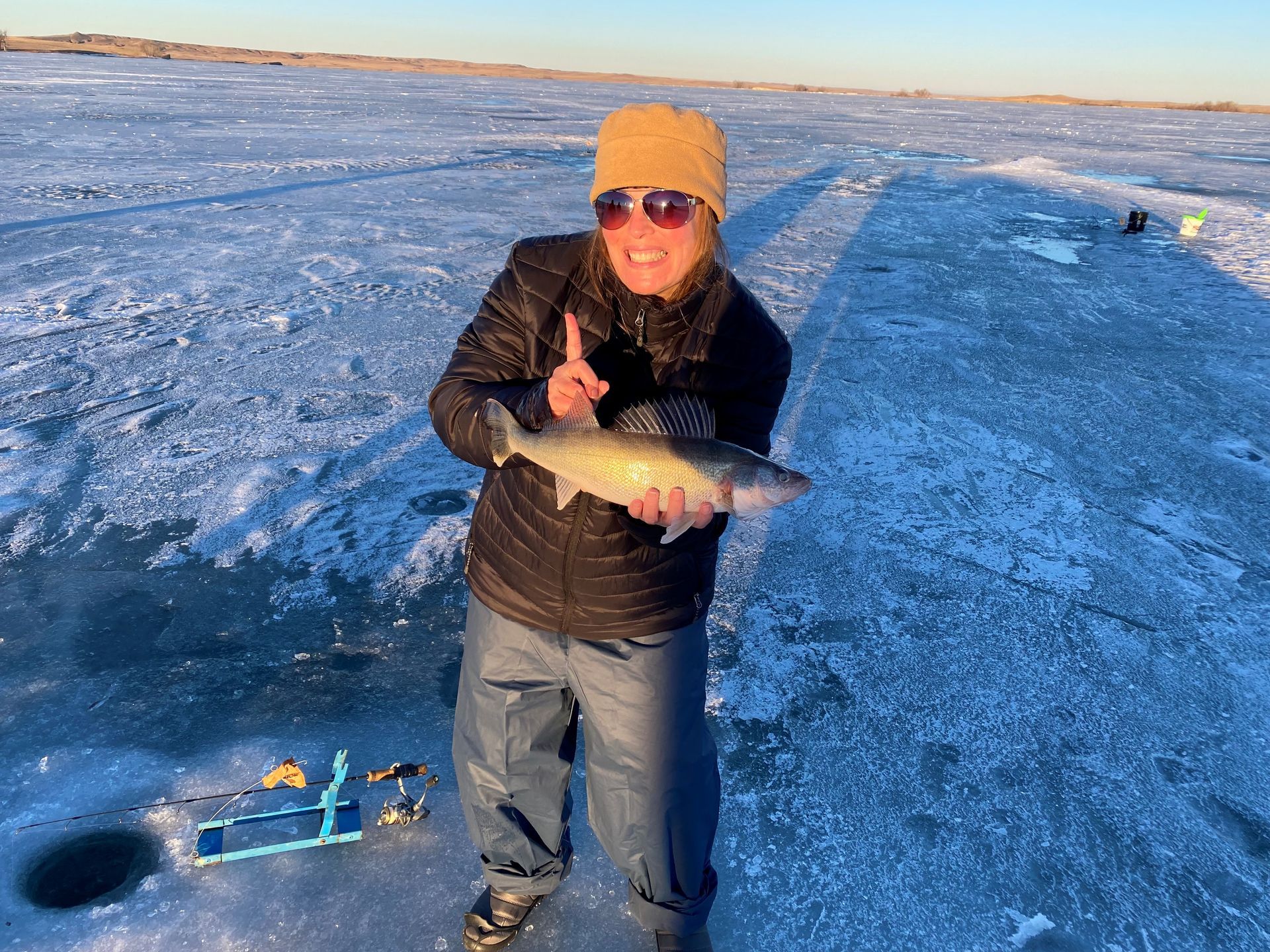 a man is standing on a frozen lake holding a fish.