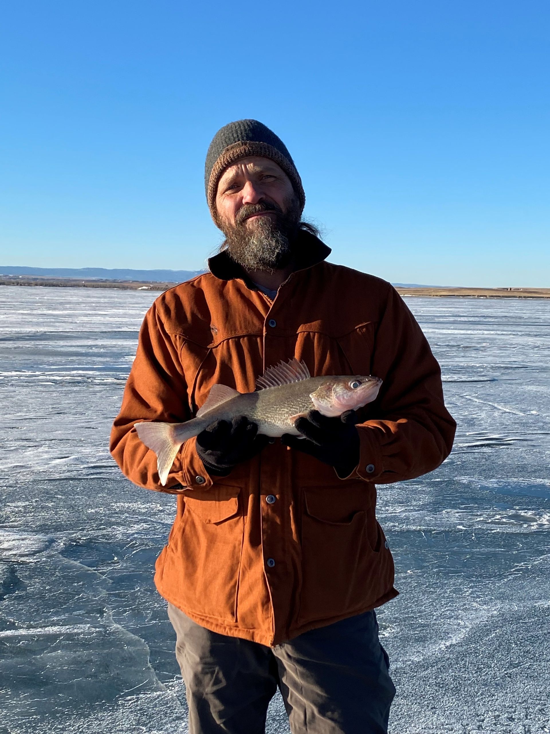 a man in a brown jacket is holding a fish in his hands.