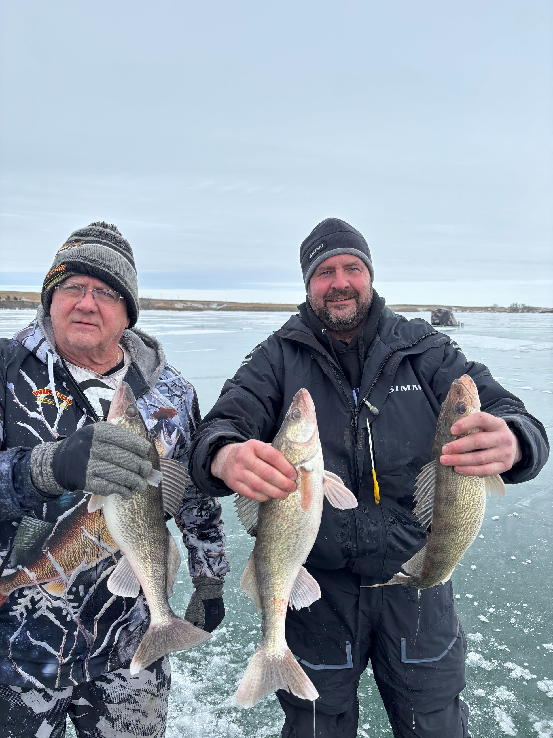 two men are holding fish in their hands on a boat.
