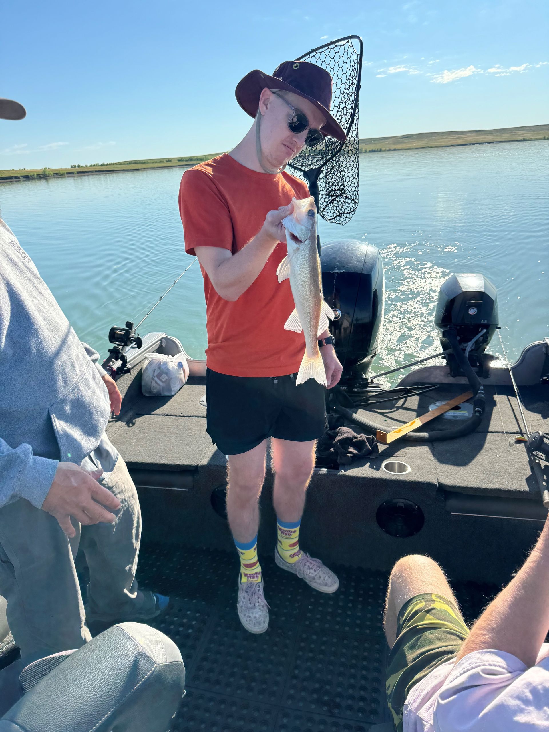 A man is standing on a boat holding a fish