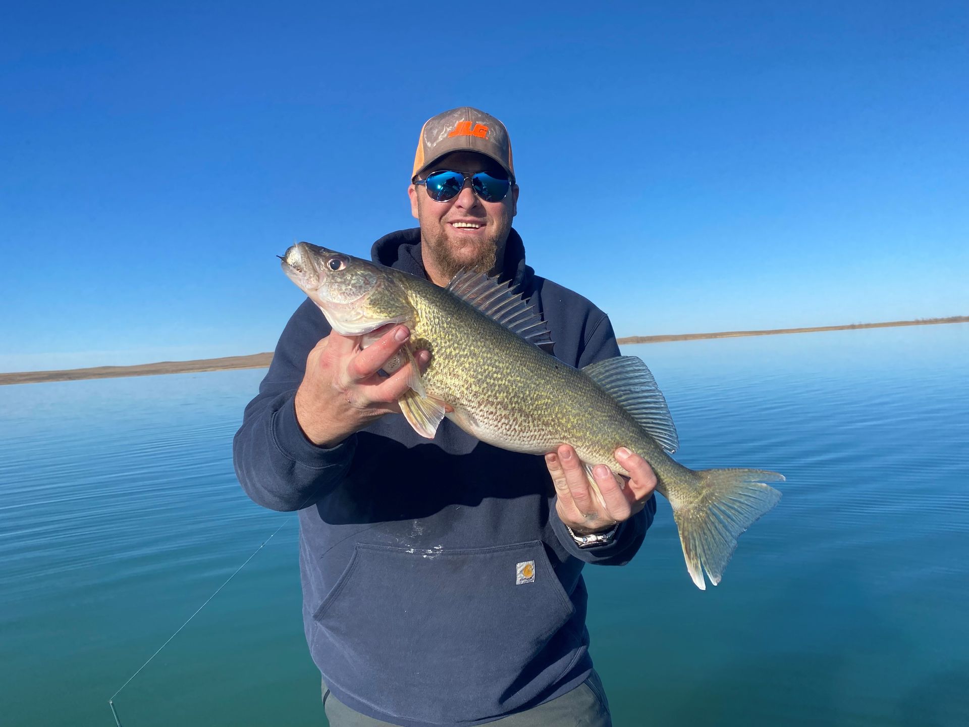 a man is holding a large fish in his hands on a lake.