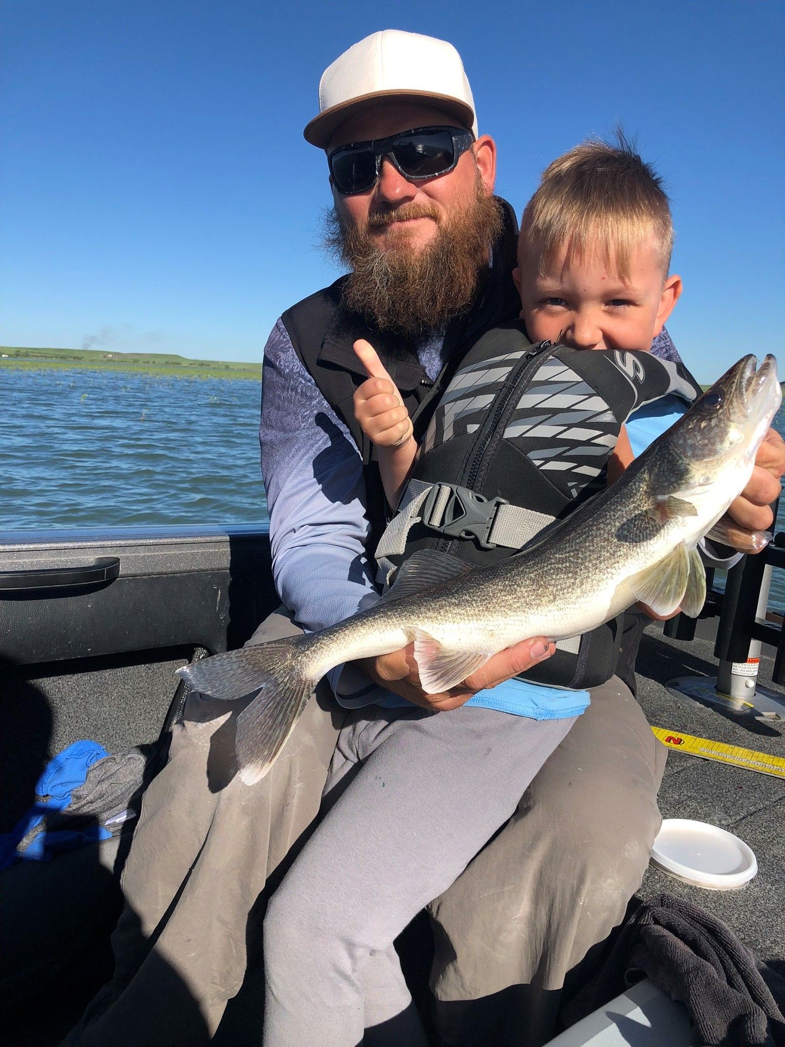 a man and a boy are sitting on a boat holding a fish.