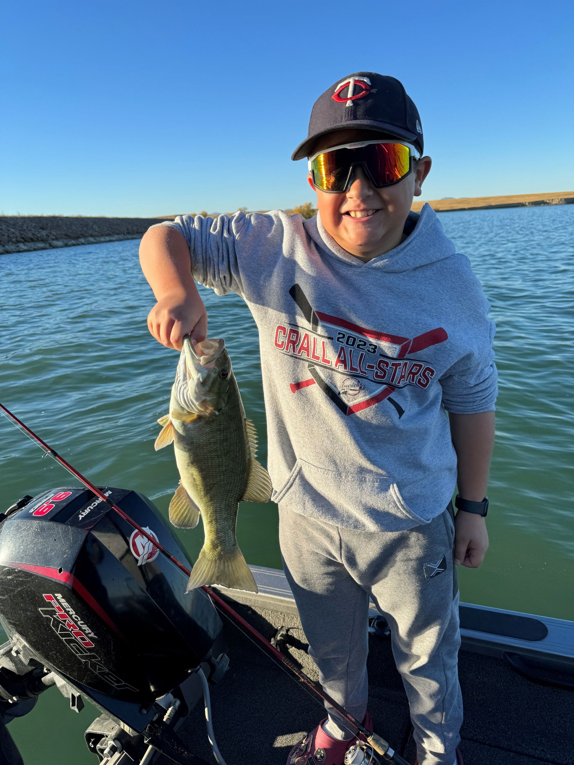 a young boy is standing on a boat holding a fish.