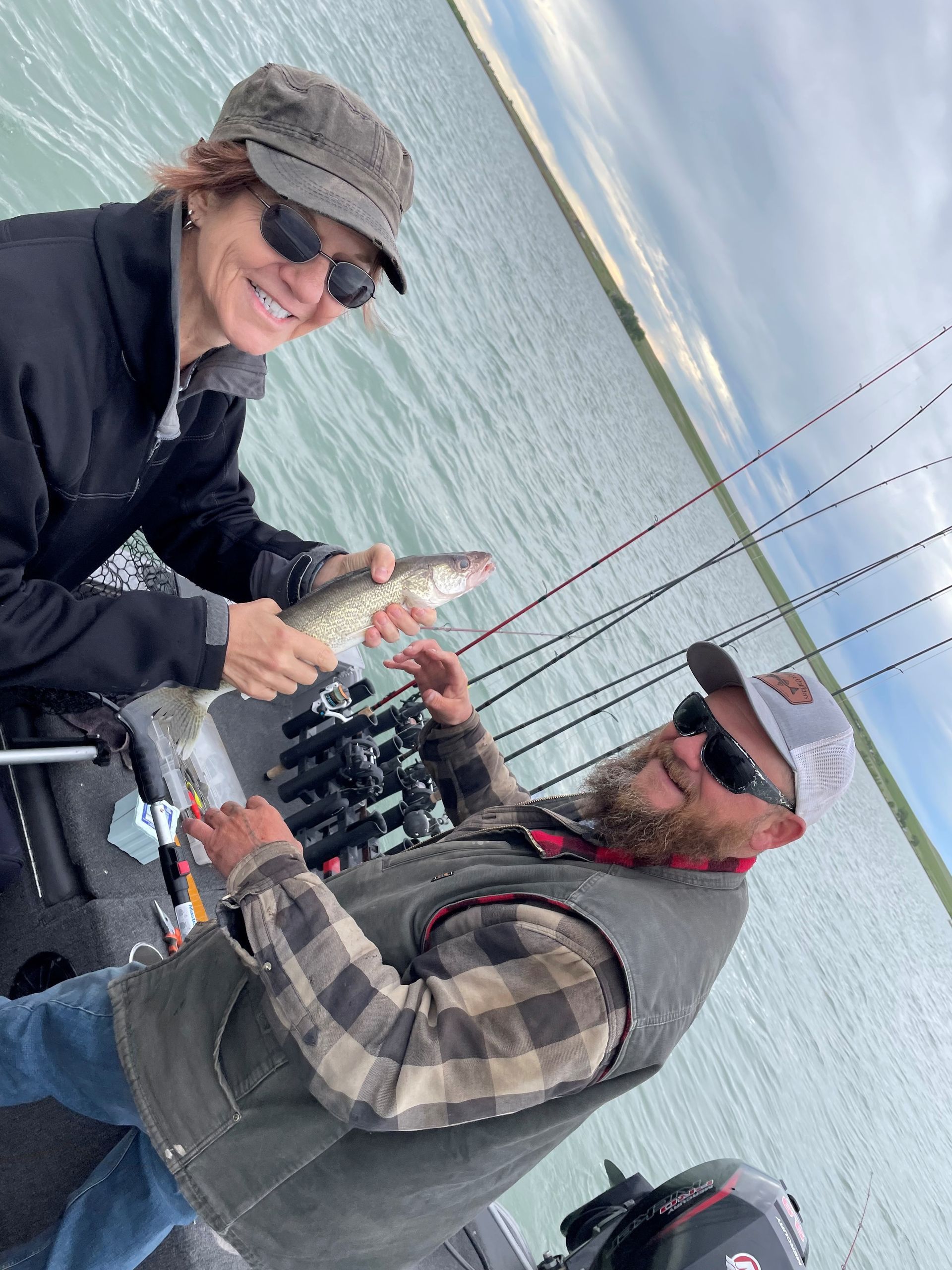 A man and a woman are fishing on a boat