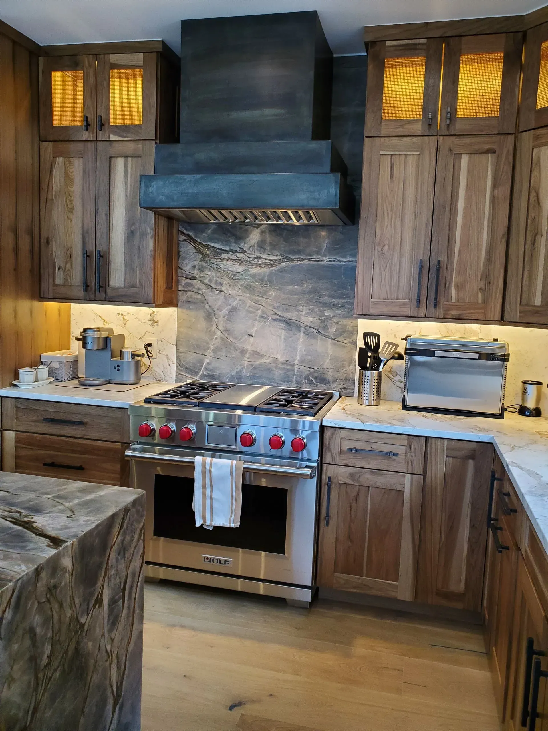 Kitchen with rustic wooden cabinets, stainless steel range, and granite backsplash.