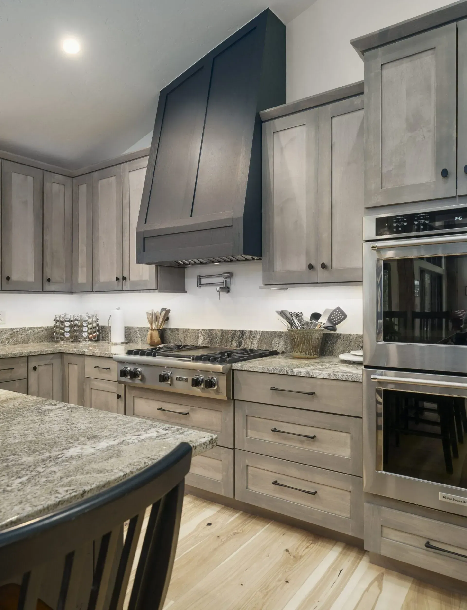 Gray kitchen with stainless steel appliances, granite countertops, and light wood flooring.