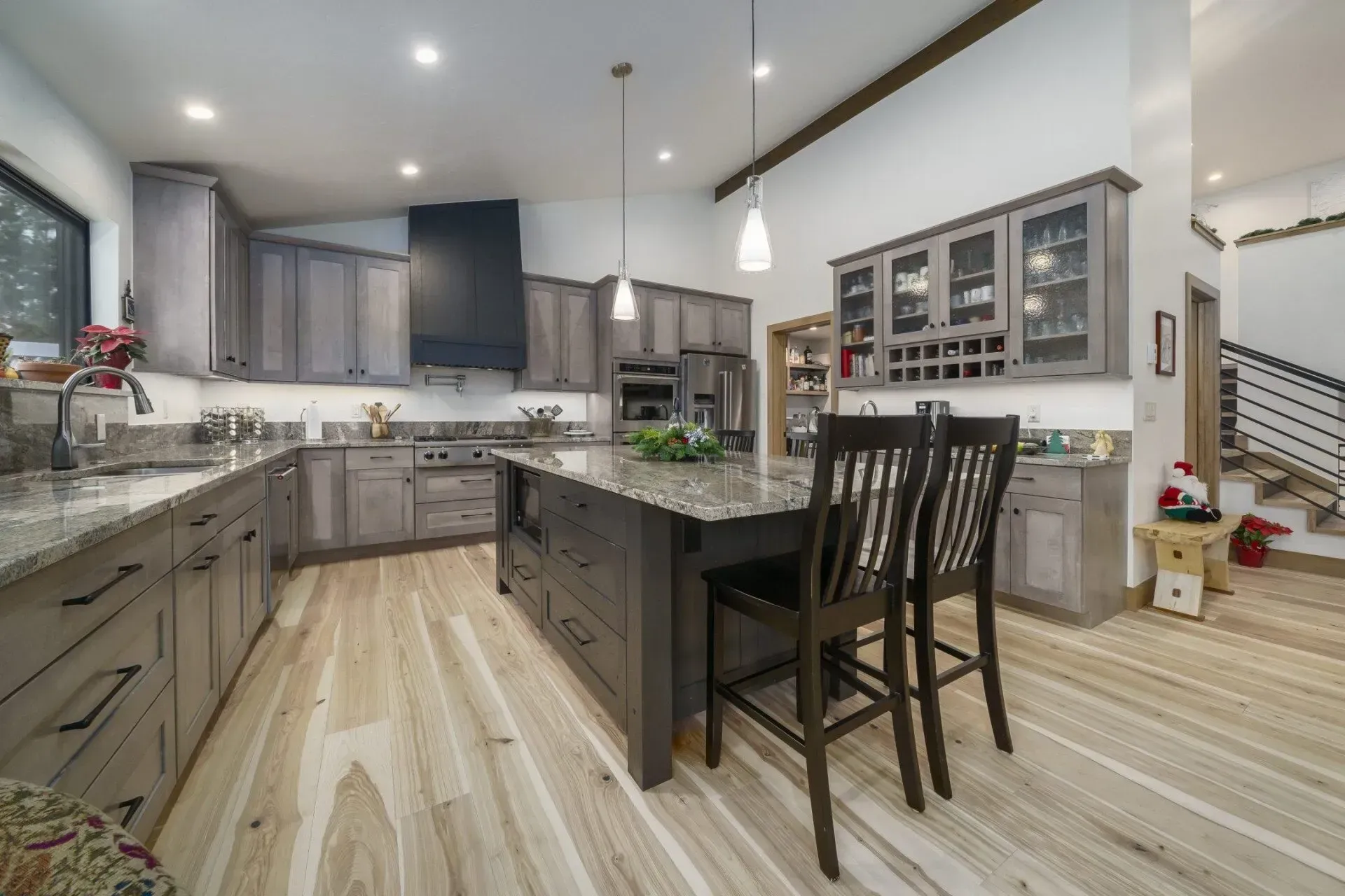 Spacious modern kitchen with gray cabinets, granite countertops, island, and wood floors.