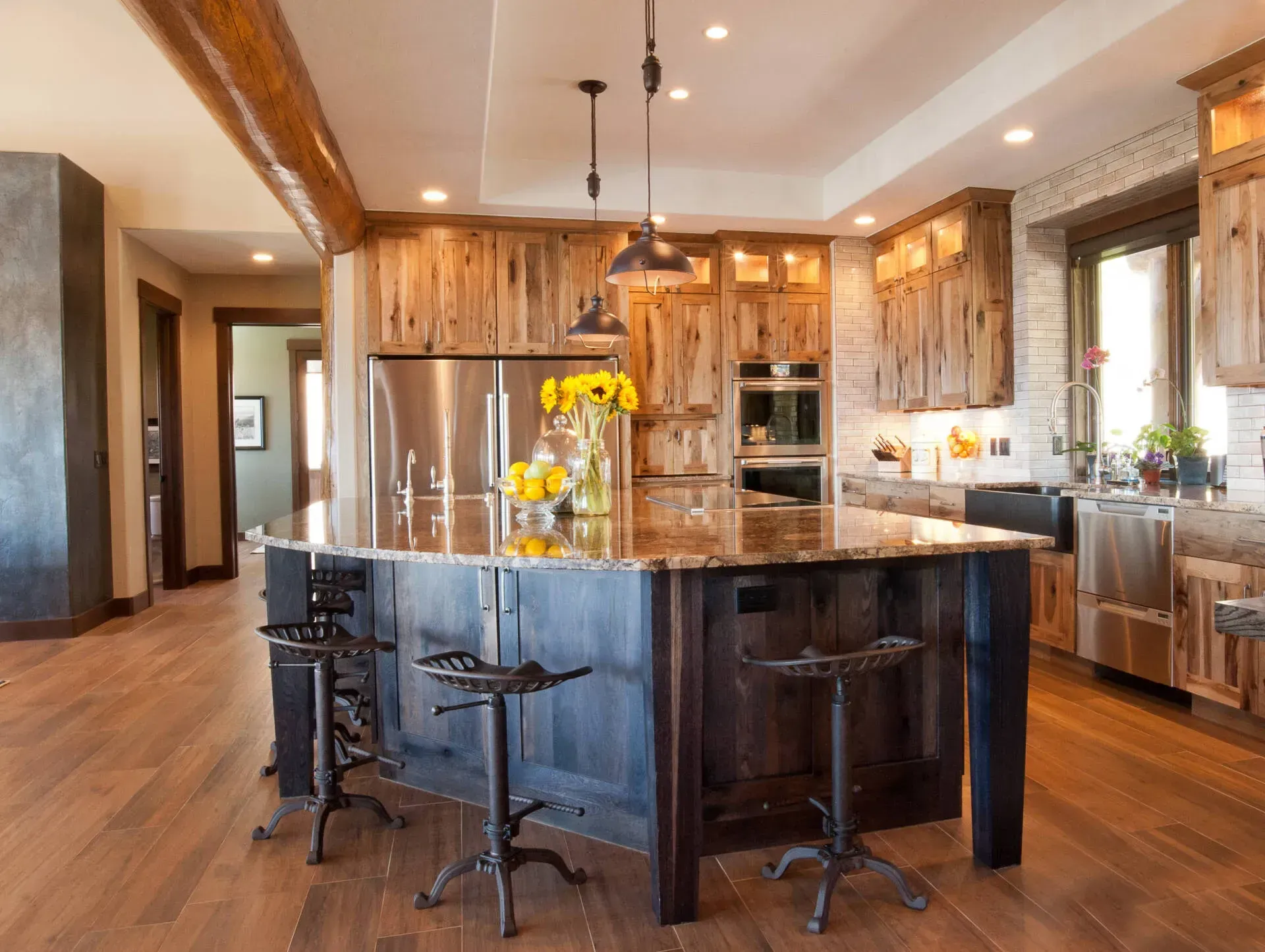 Rustic kitchen with wood cabinets, granite island, and stools.