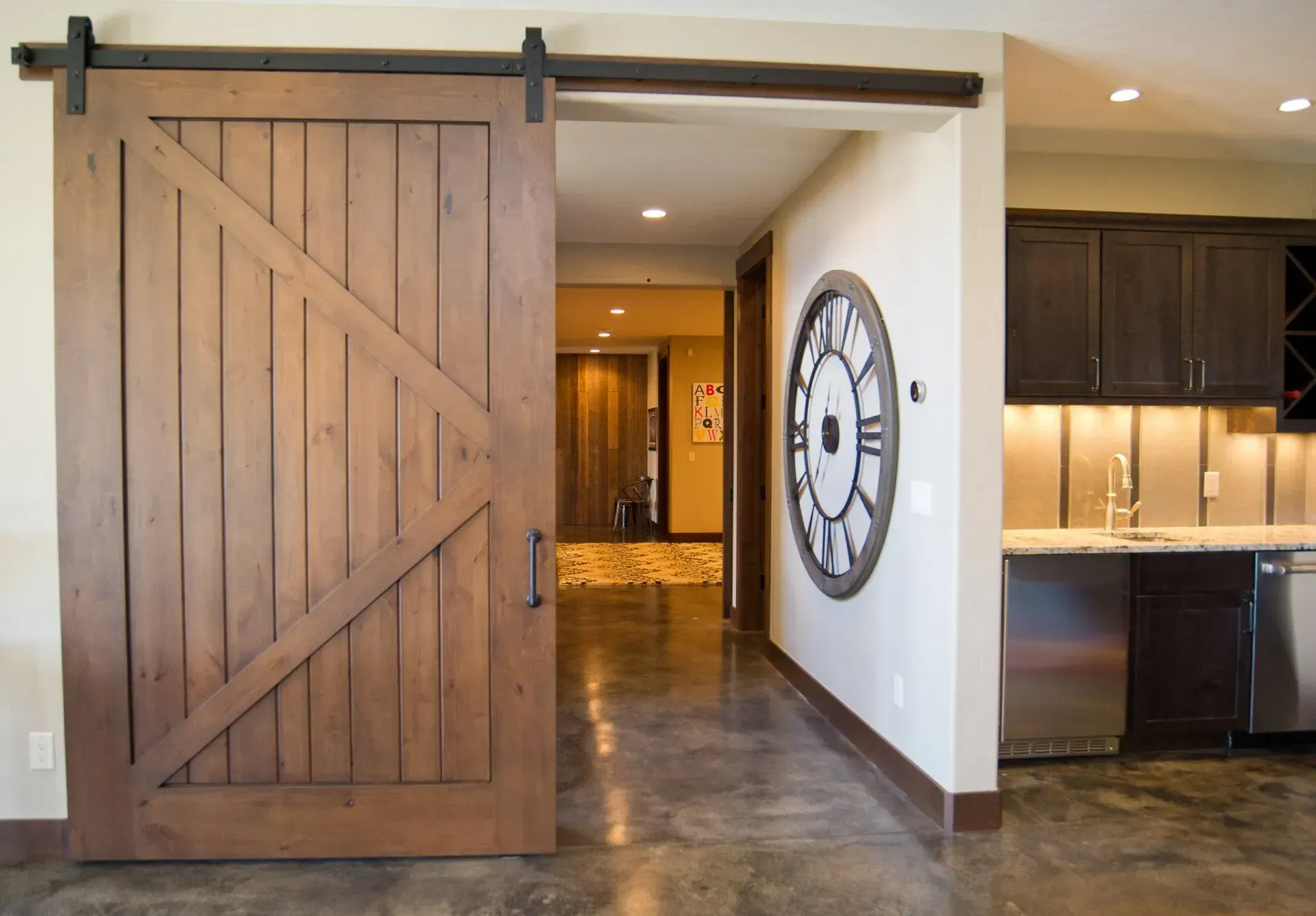 Rustic wooden sliding barn door partially open, revealing a hallway.