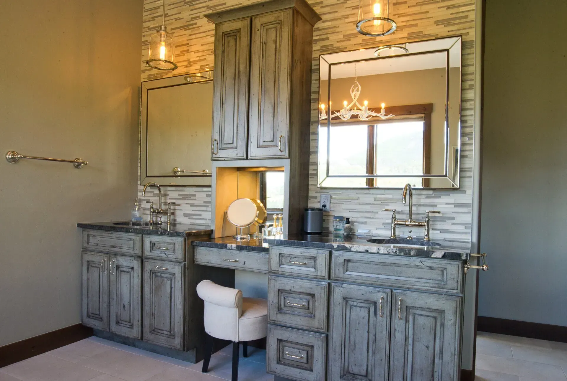 Bathroom with gray distressed cabinets, backsplash, mirrors, and vanity; soft beige walls.