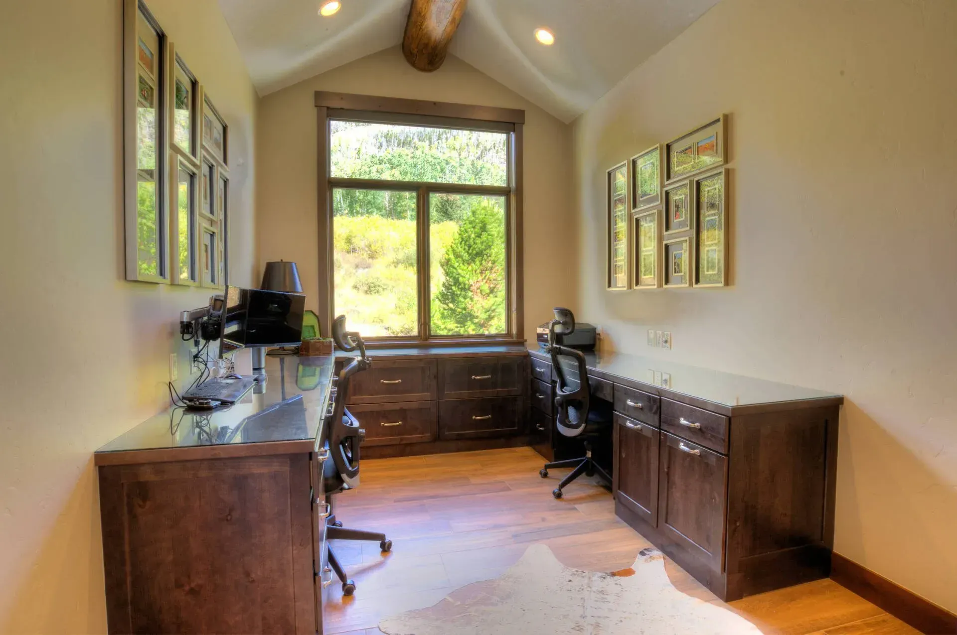 Office space with two desks, window, and wood cabinetry; neutral colors, natural light.
