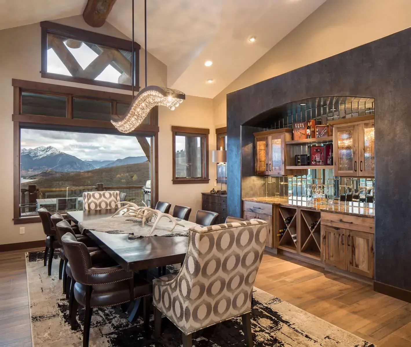 Dining room with long table, mountain view, built-in bar, and modern light fixture.