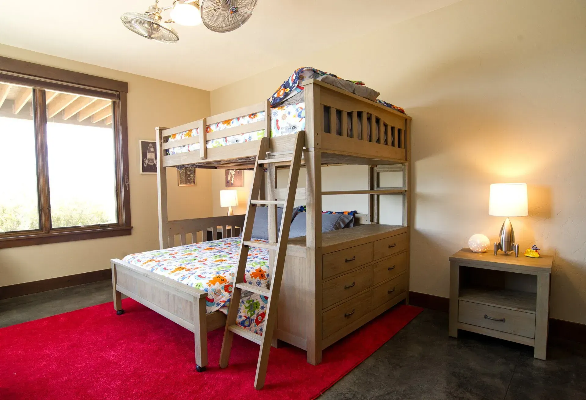 Bunk bed with wooden frame, red rug, nightstand with lamp in a bedroom.