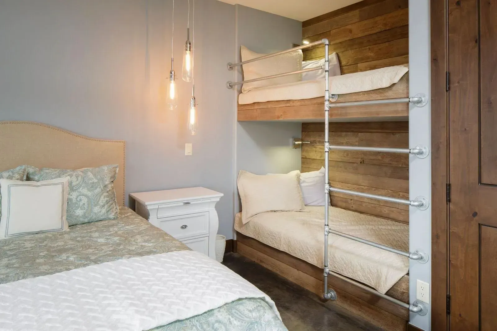 Bedroom with a bed, a bunk bed, and a wooden accent wall.