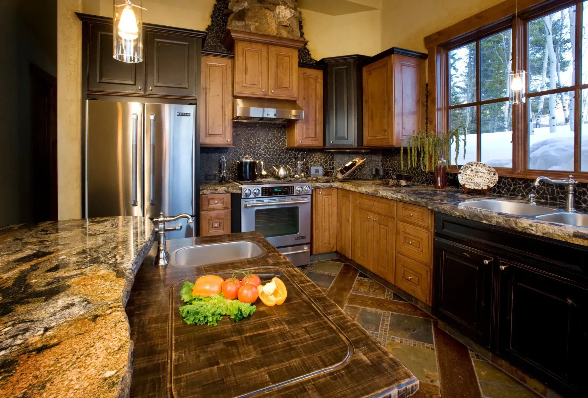 Kitchen with dark wood cabinets, granite countertops, stainless steel appliances, and a window with a snowy view.