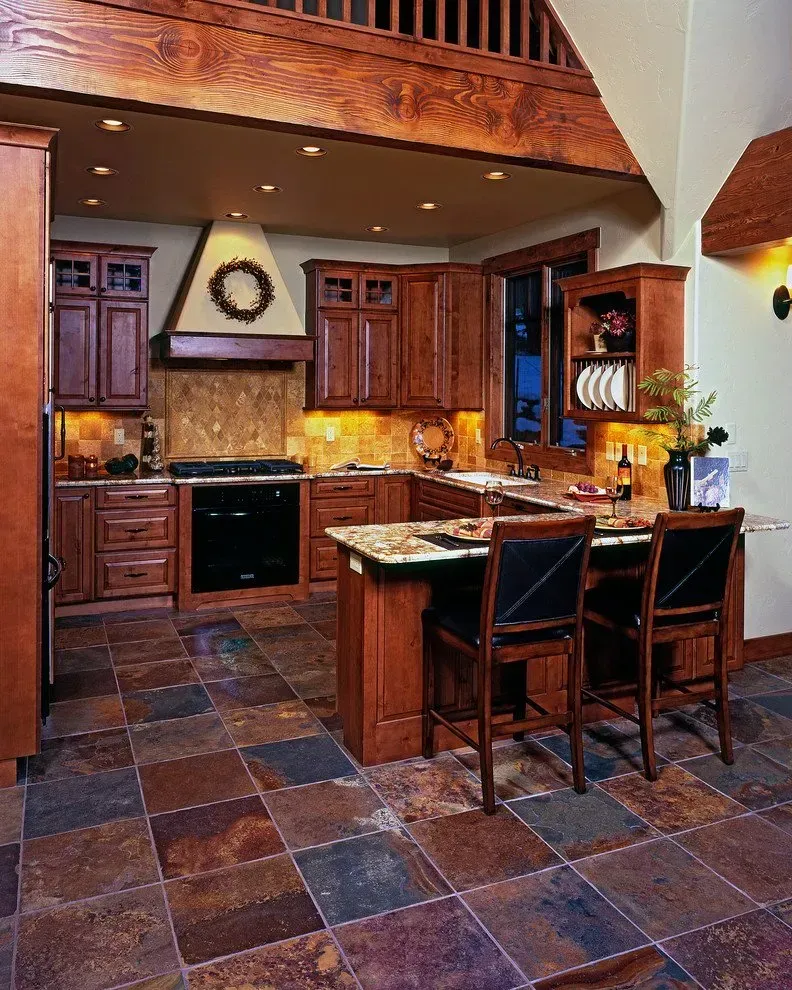 Kitchen with wood cabinets, stone floor, and a breakfast bar.