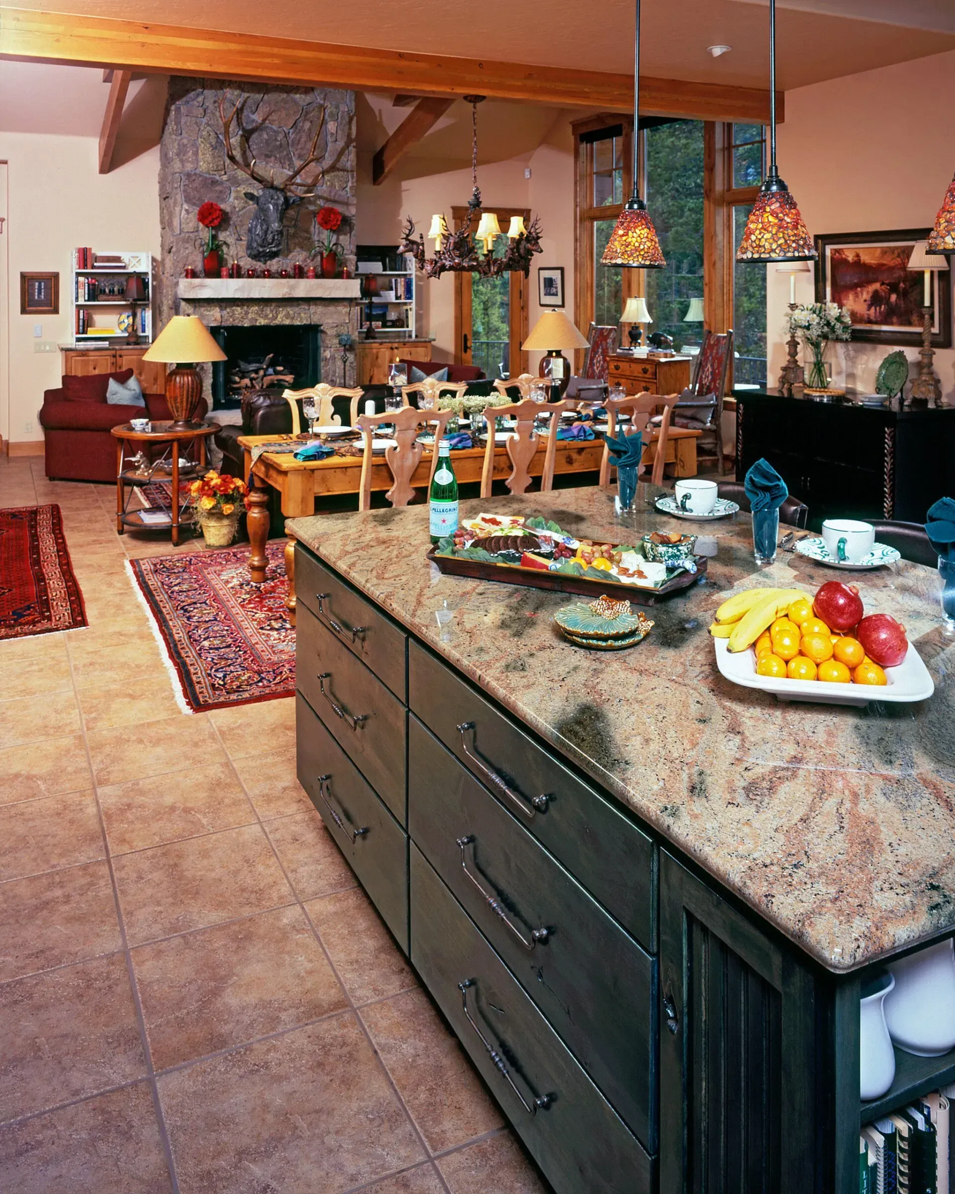 Kitchen with island, fireplace, dining area. Cabinets, granite countertop, fruit, and rug.