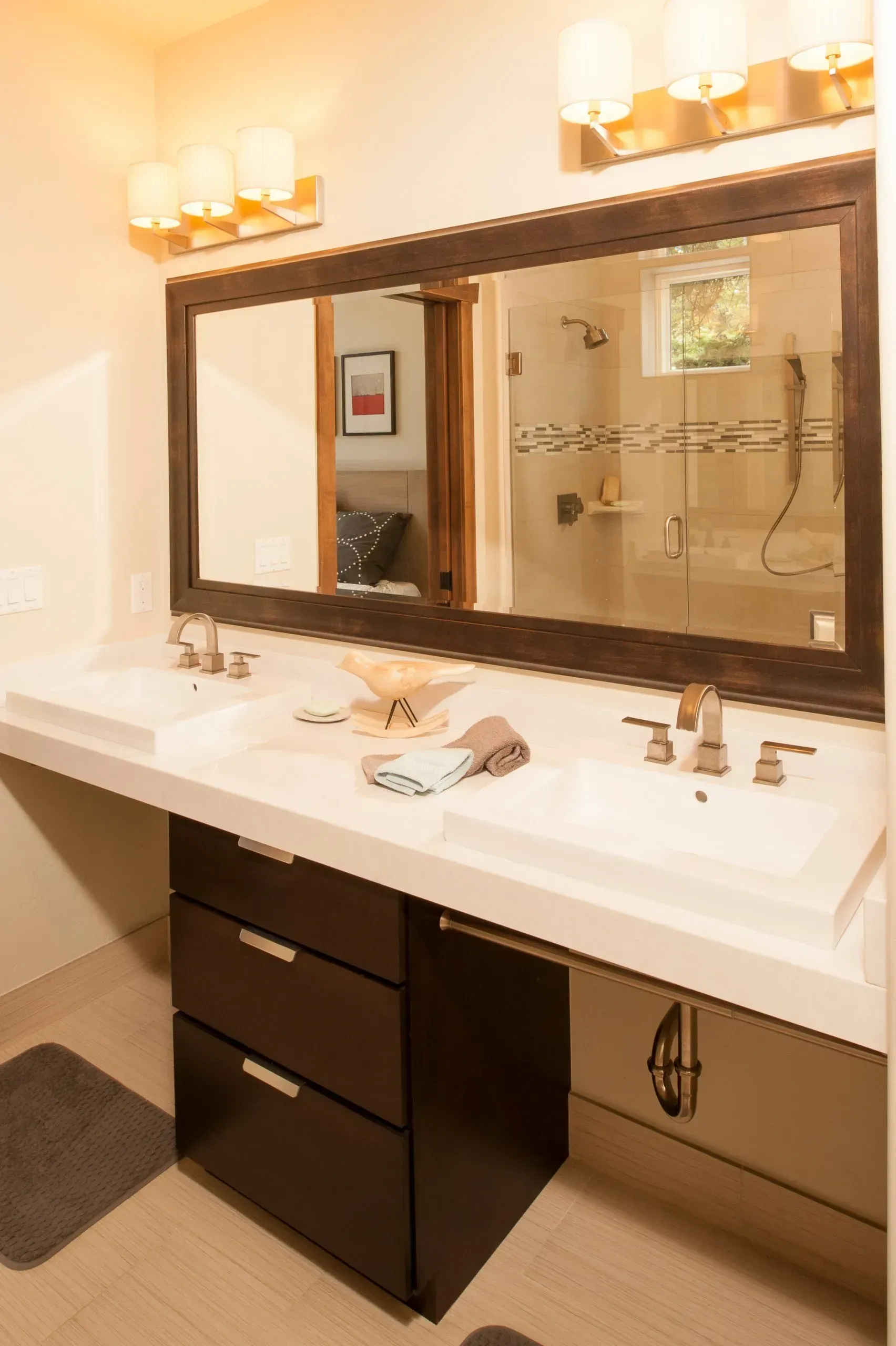 Bathroom with double sinks, large mirror, brown cabinets, and warm lighting.