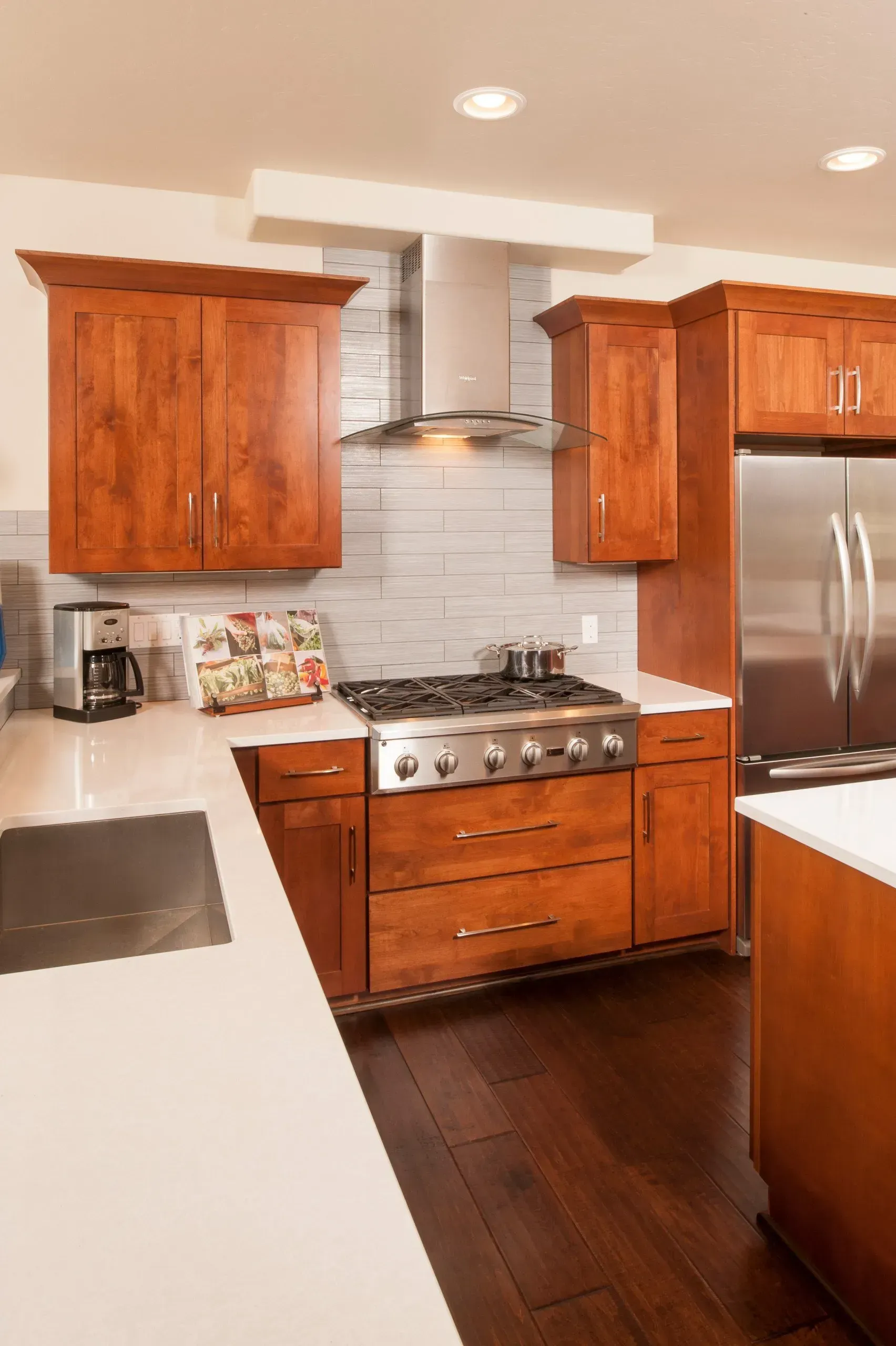 Kitchen with wood cabinets, stainless steel appliances, and white countertops. Dark wood flooring.