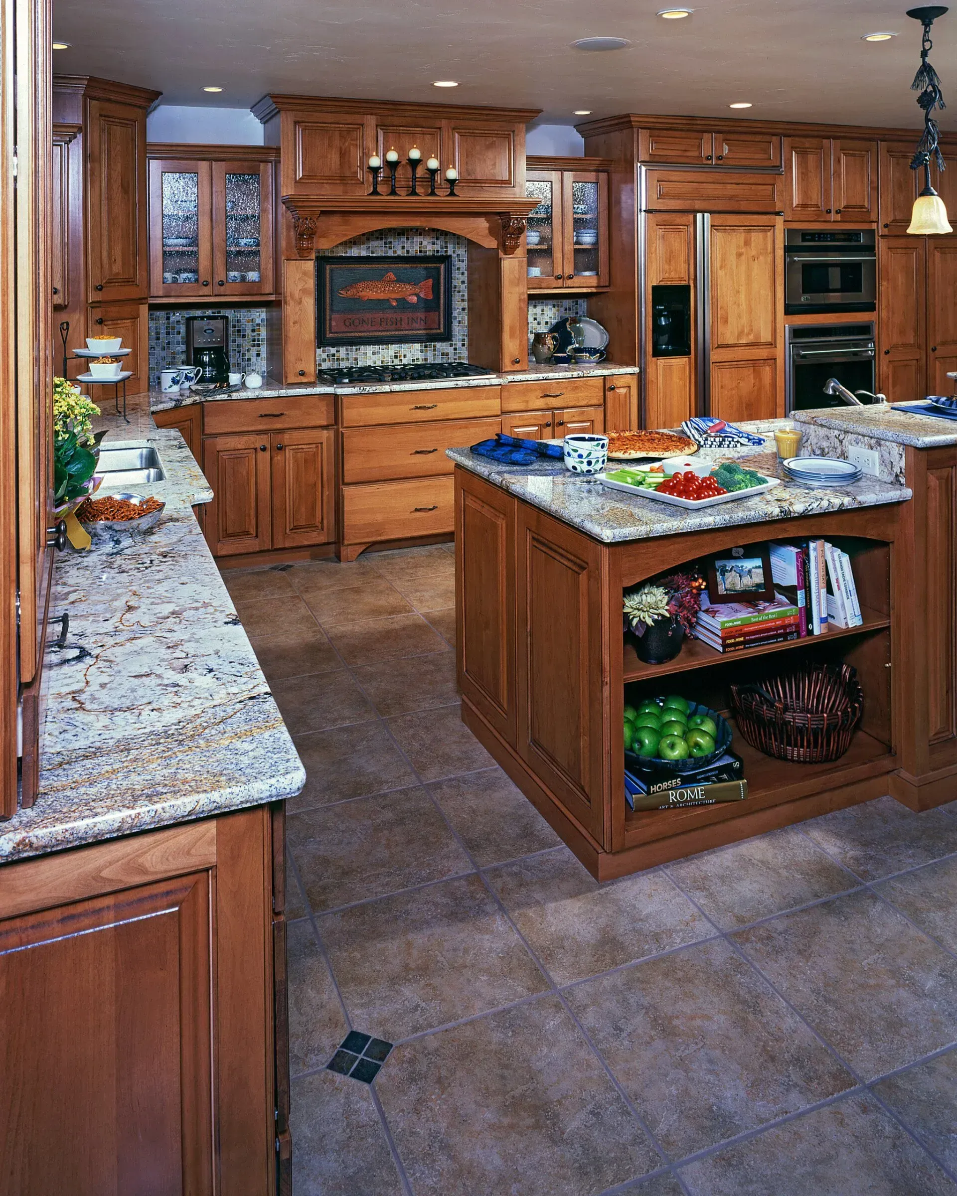 Spacious kitchen with wood cabinets, granite countertops, and island filled with snacks and fresh produce.