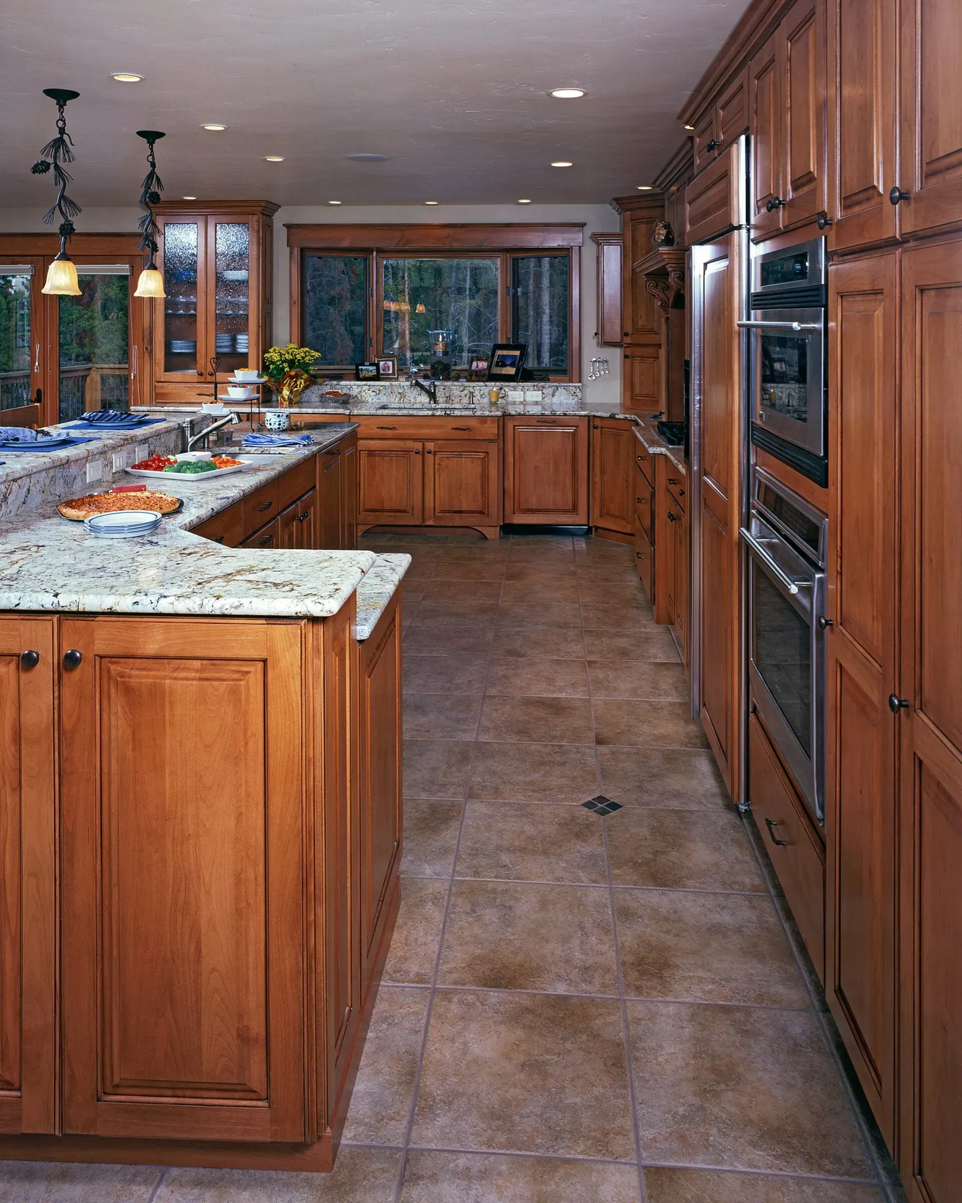 A spacious kitchen with light wood cabinets, granite countertops, and tile flooring.