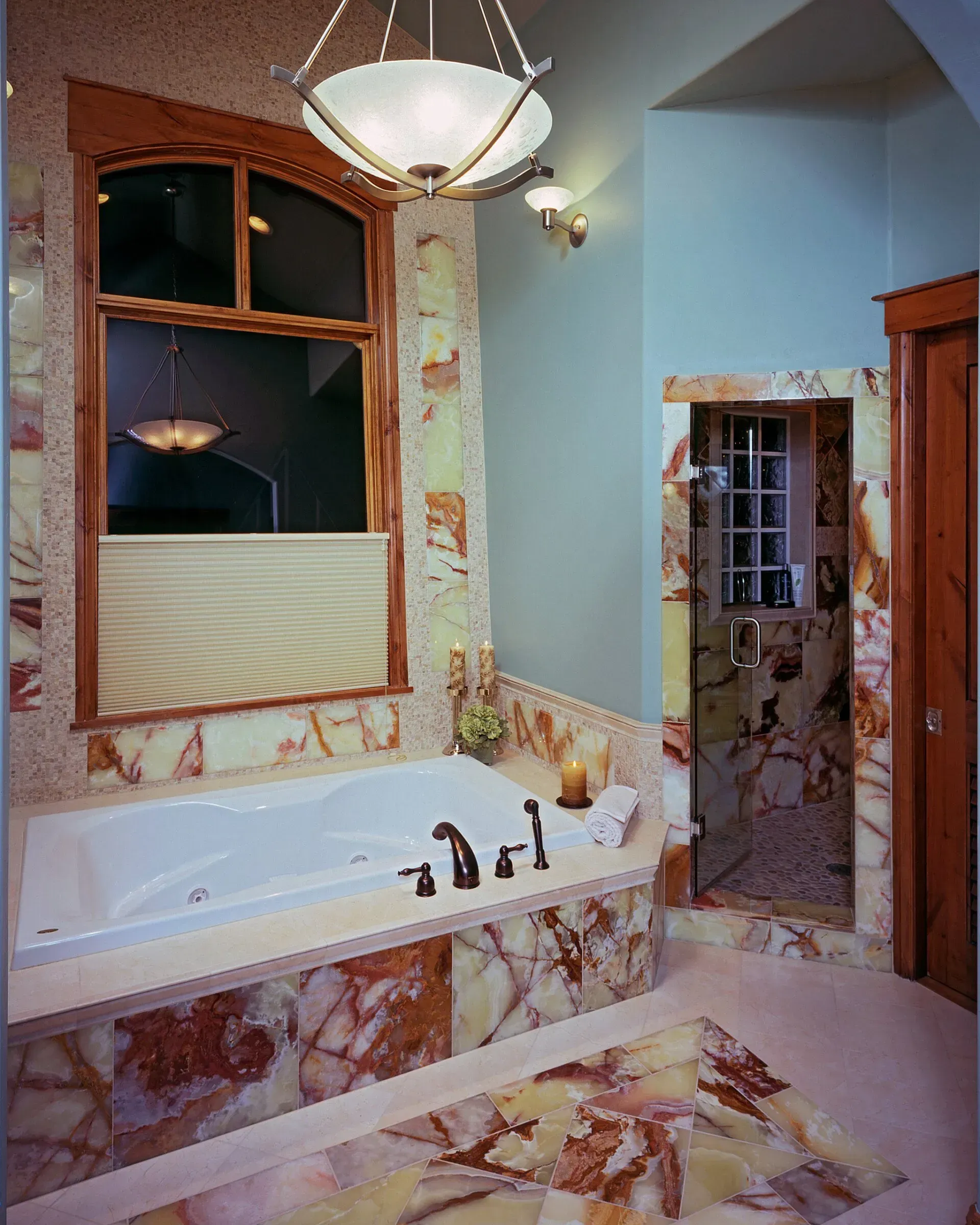 Luxury bathroom with marble walls, a jacuzzi tub, and a shower with a window.