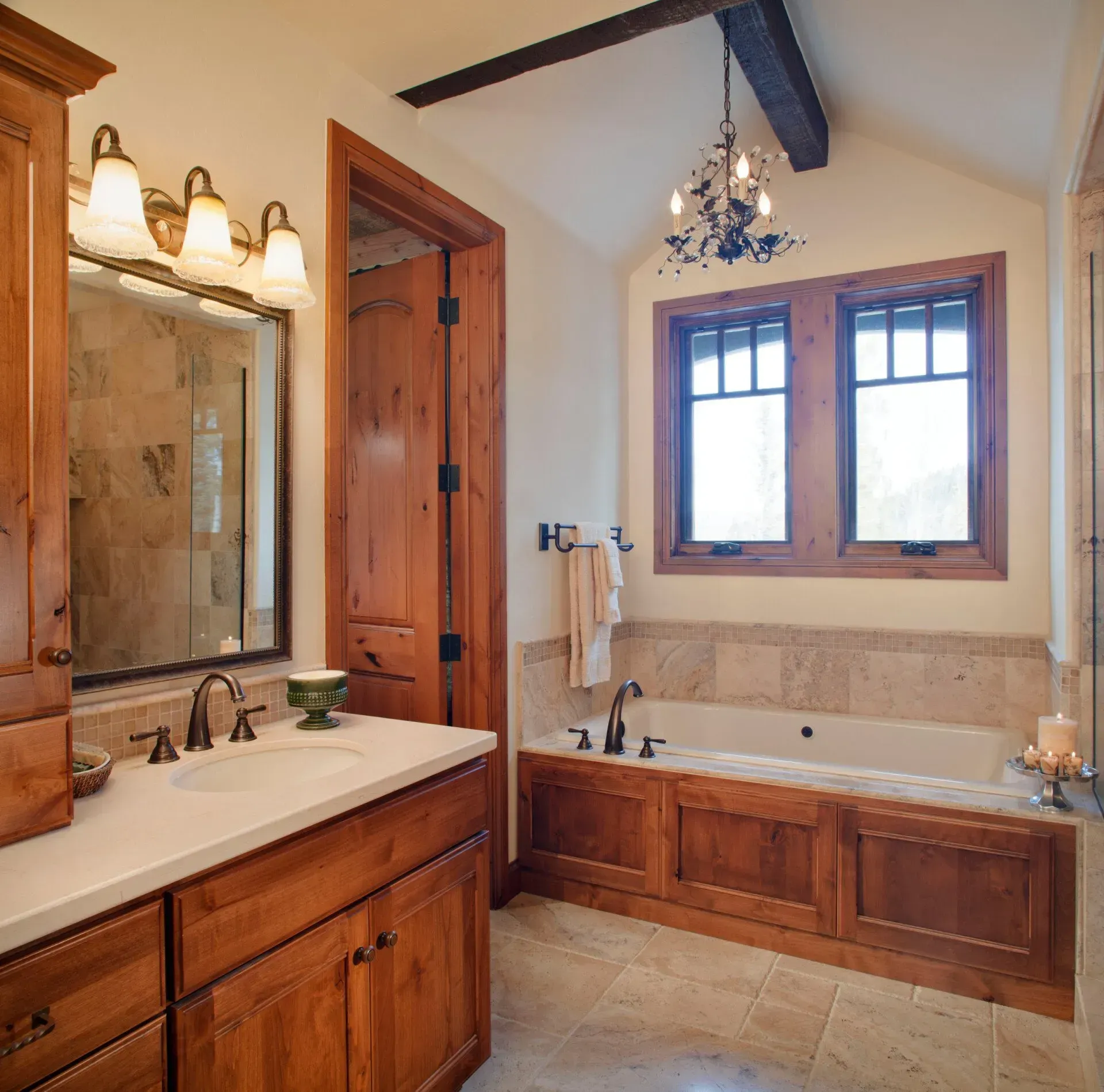 Rustic bathroom with wooden cabinets, beige tiles, a bathtub, and a window.