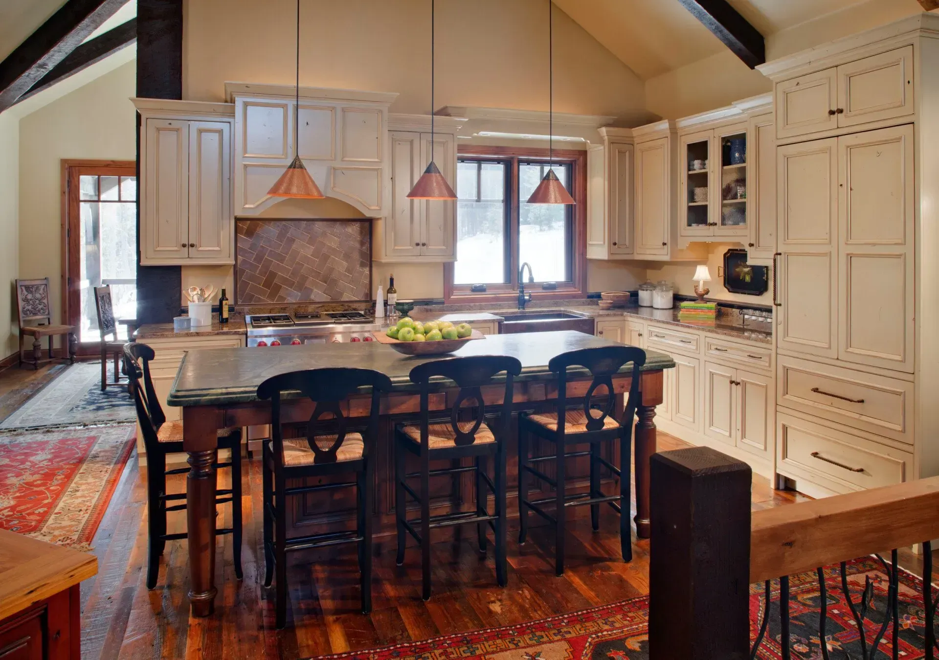 Rustic kitchen with island, cream cabinets, and copper pendant lights.