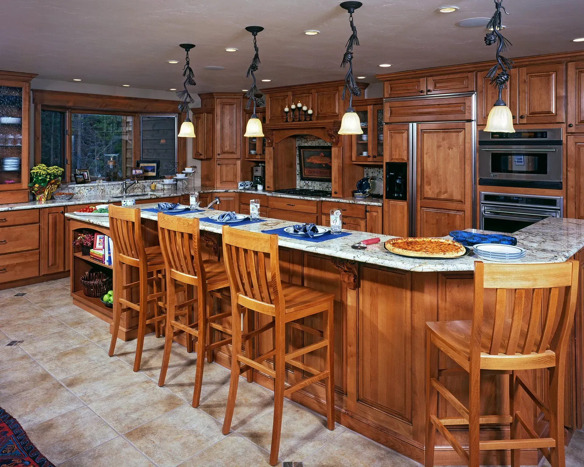 Spacious kitchen with wood cabinets, large island with seating, pendant lights, and appliances.