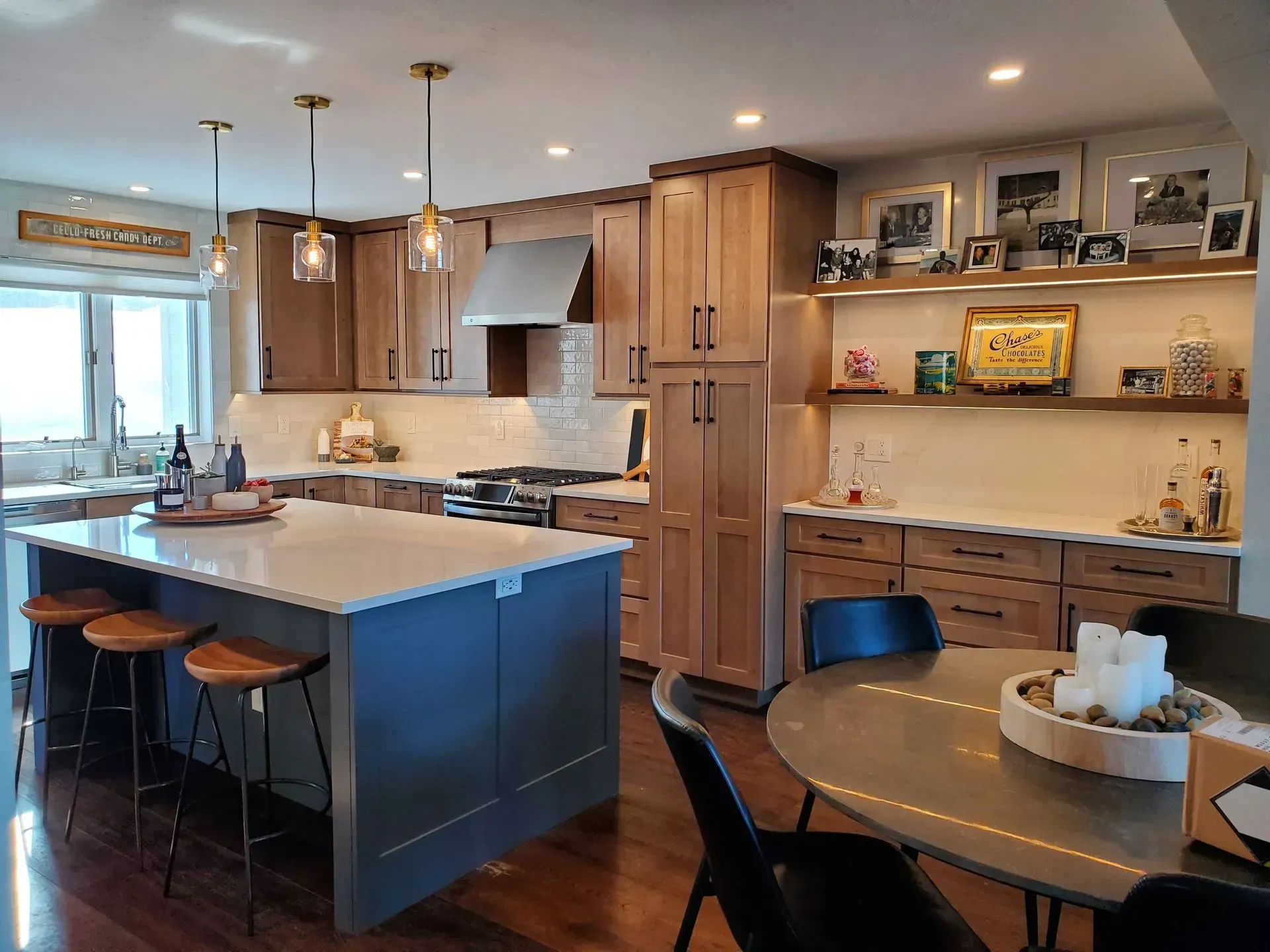 Kitchen with island, light wood cabinets, and gray island base, stainless steel appliances, and round dining table.