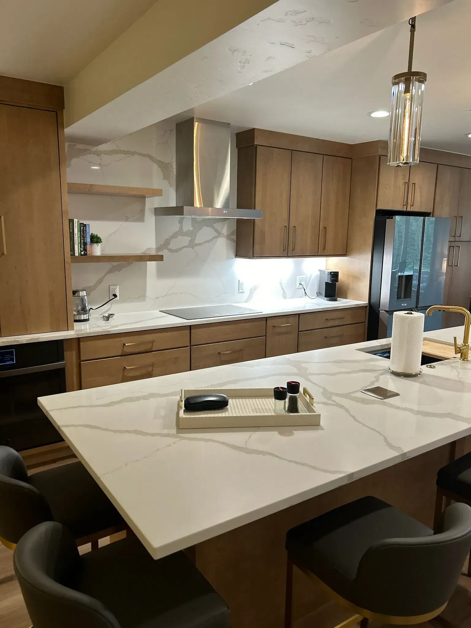 Modern kitchen with light wood cabinets, white countertops, and stainless steel appliances.