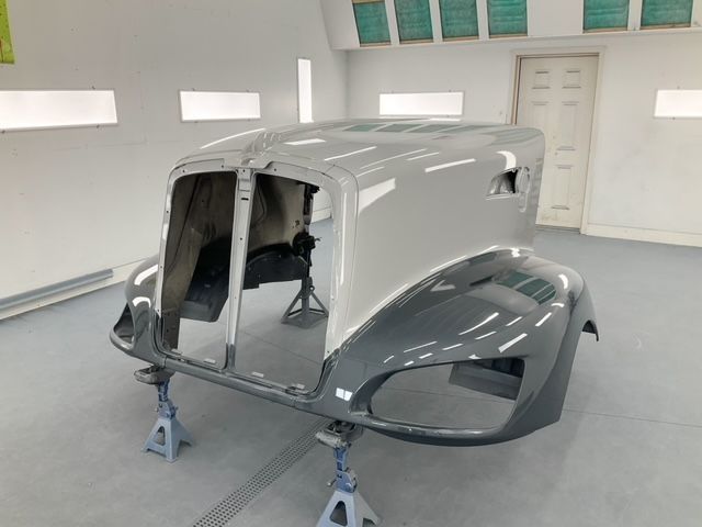 Car body in a paint booth, partially assembled, gray and light gray paint.
