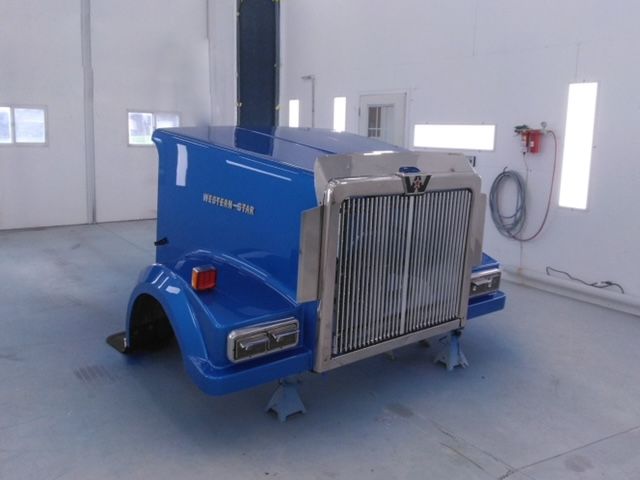 Fiberglass repair work and custom paint job completed on front end of a blue semi-truck