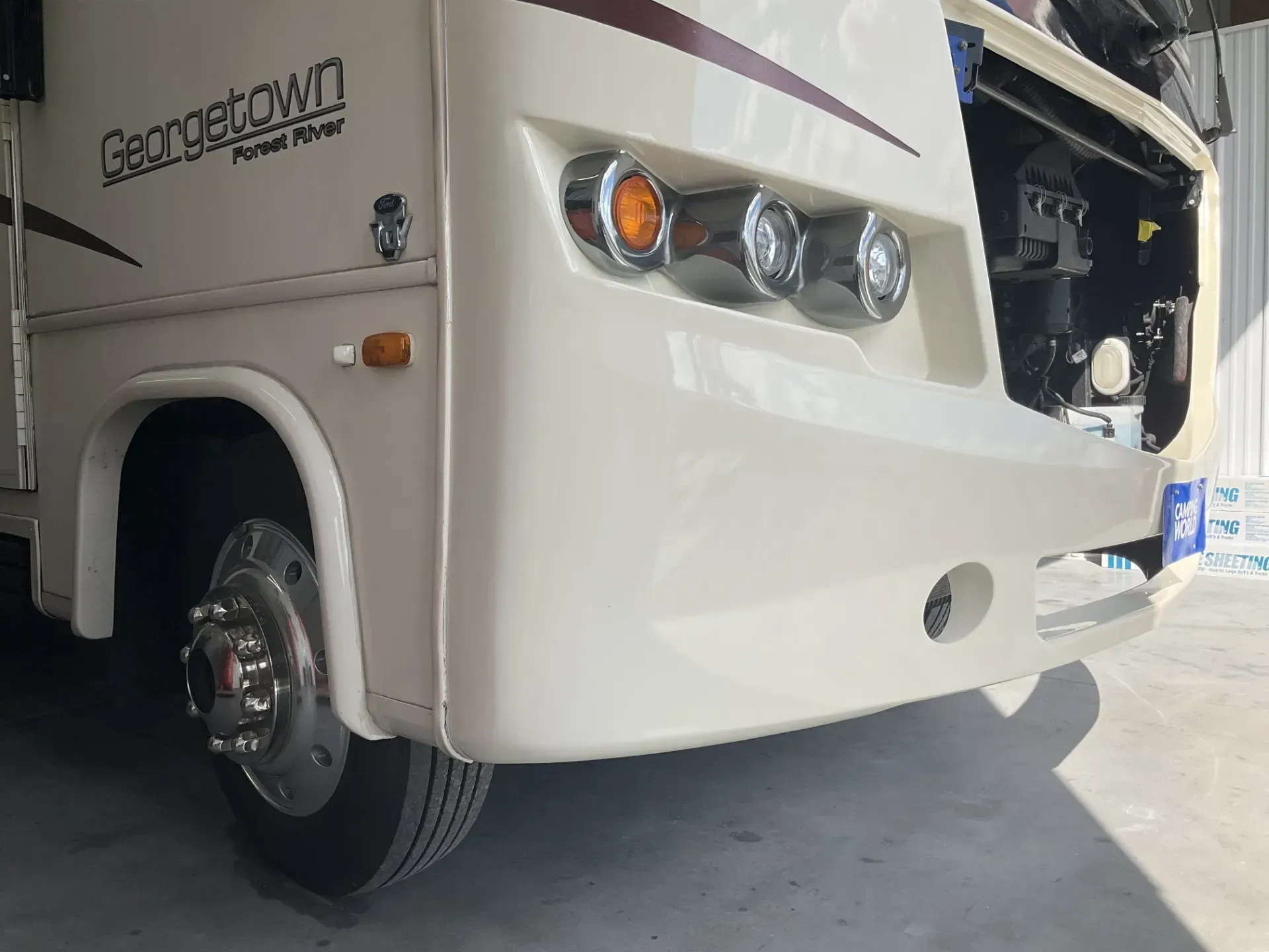 Cream-colored Georgetown motorhome front view, showing headlights, tire, and wheel.