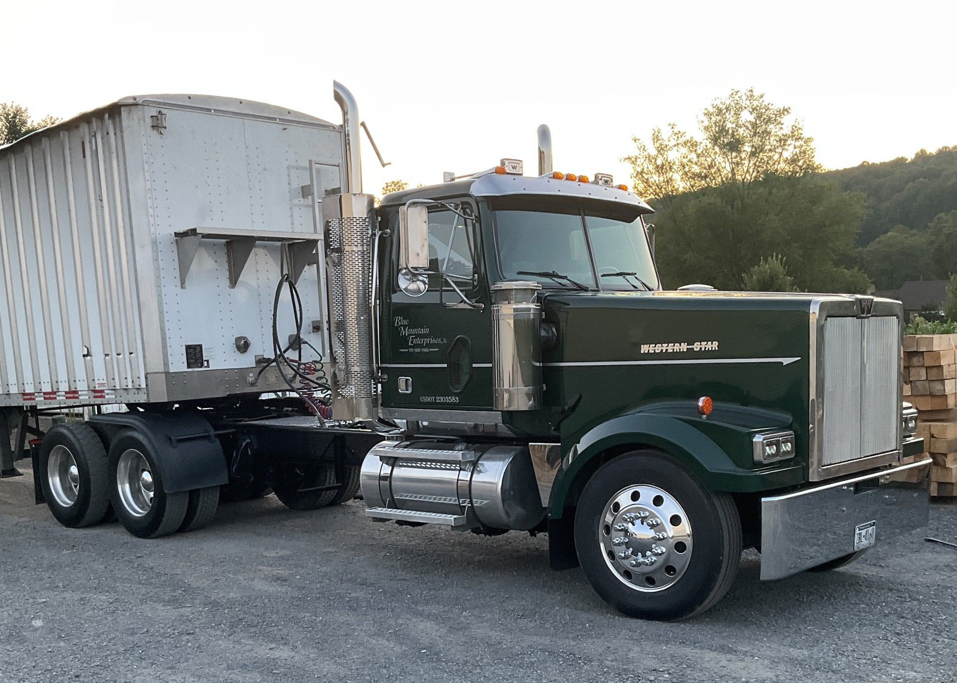 Dark green semi-truck with a white trailer parked outdoors.